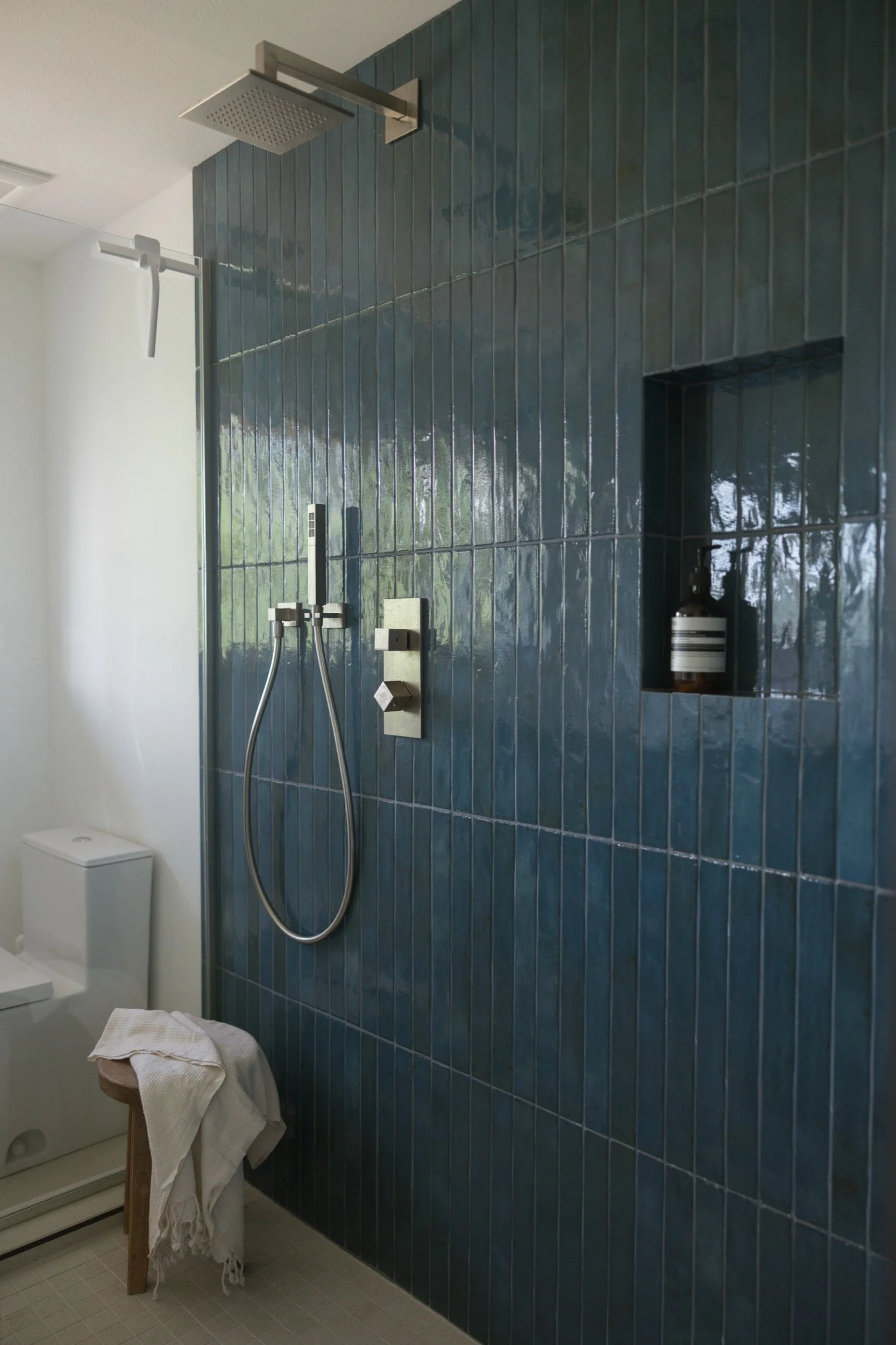 Blue tile shower with brushed nickel fixtures and a built-in niche