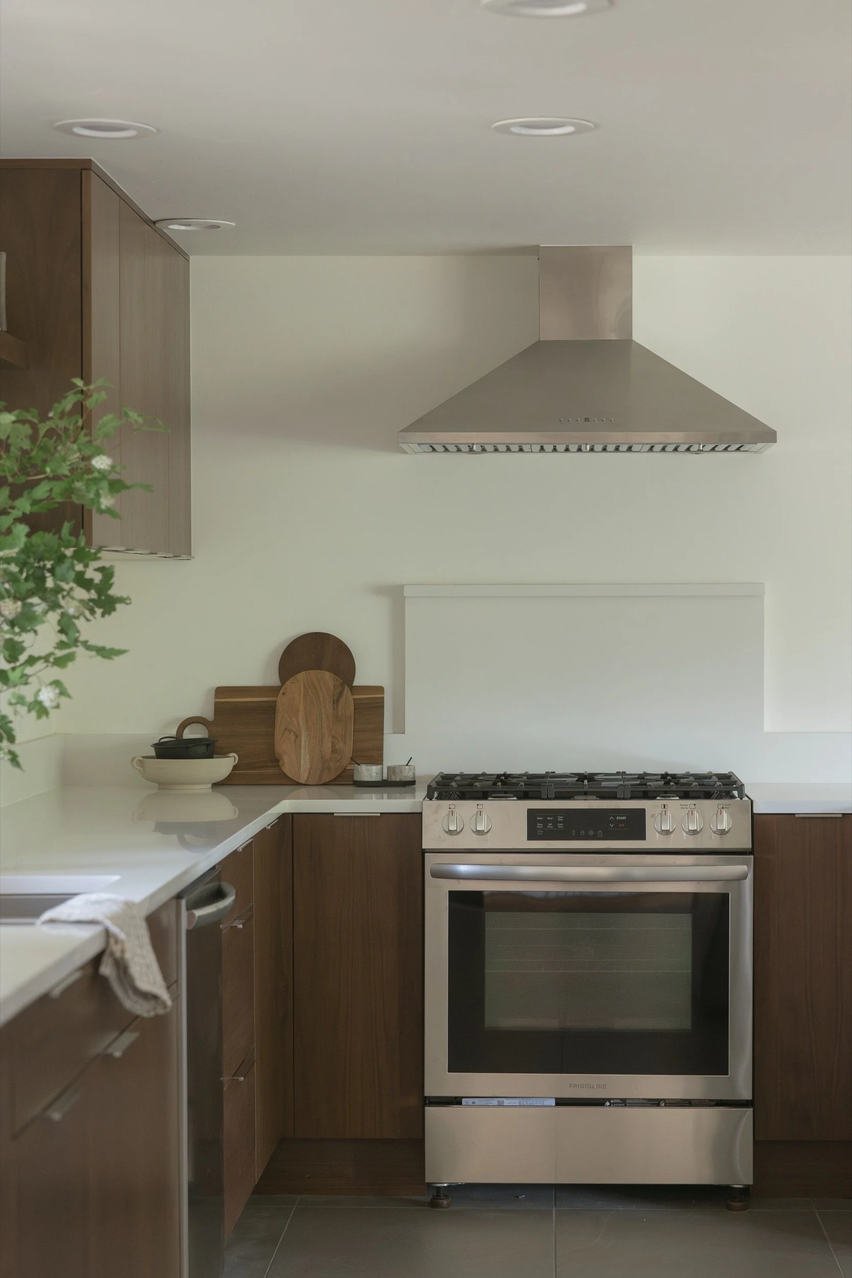 Range wall with walnut cabinets and quartz counters in a remodeled Hood River kitchen