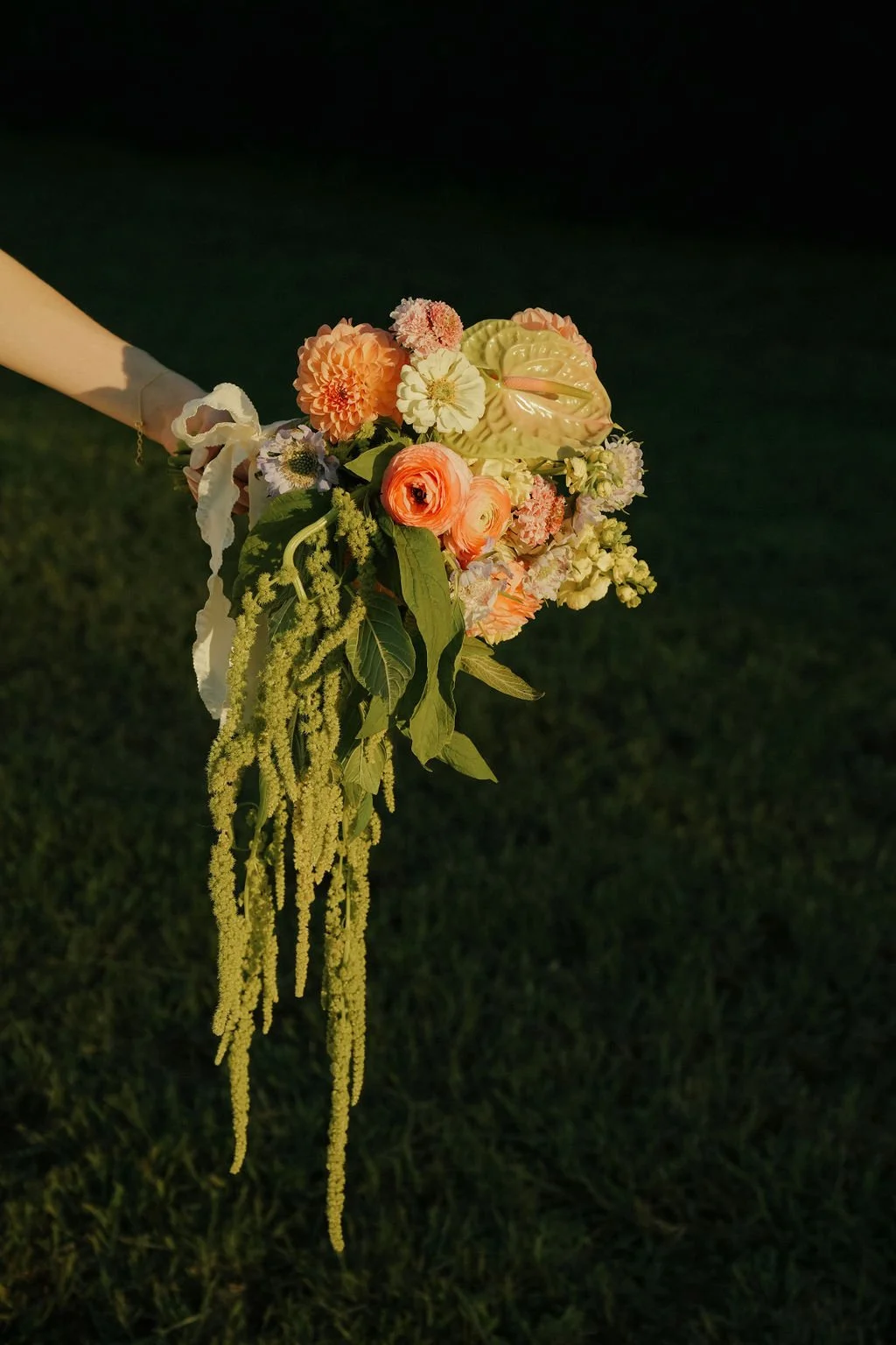 Bouquet of colorful flowers with greenery against grass background.