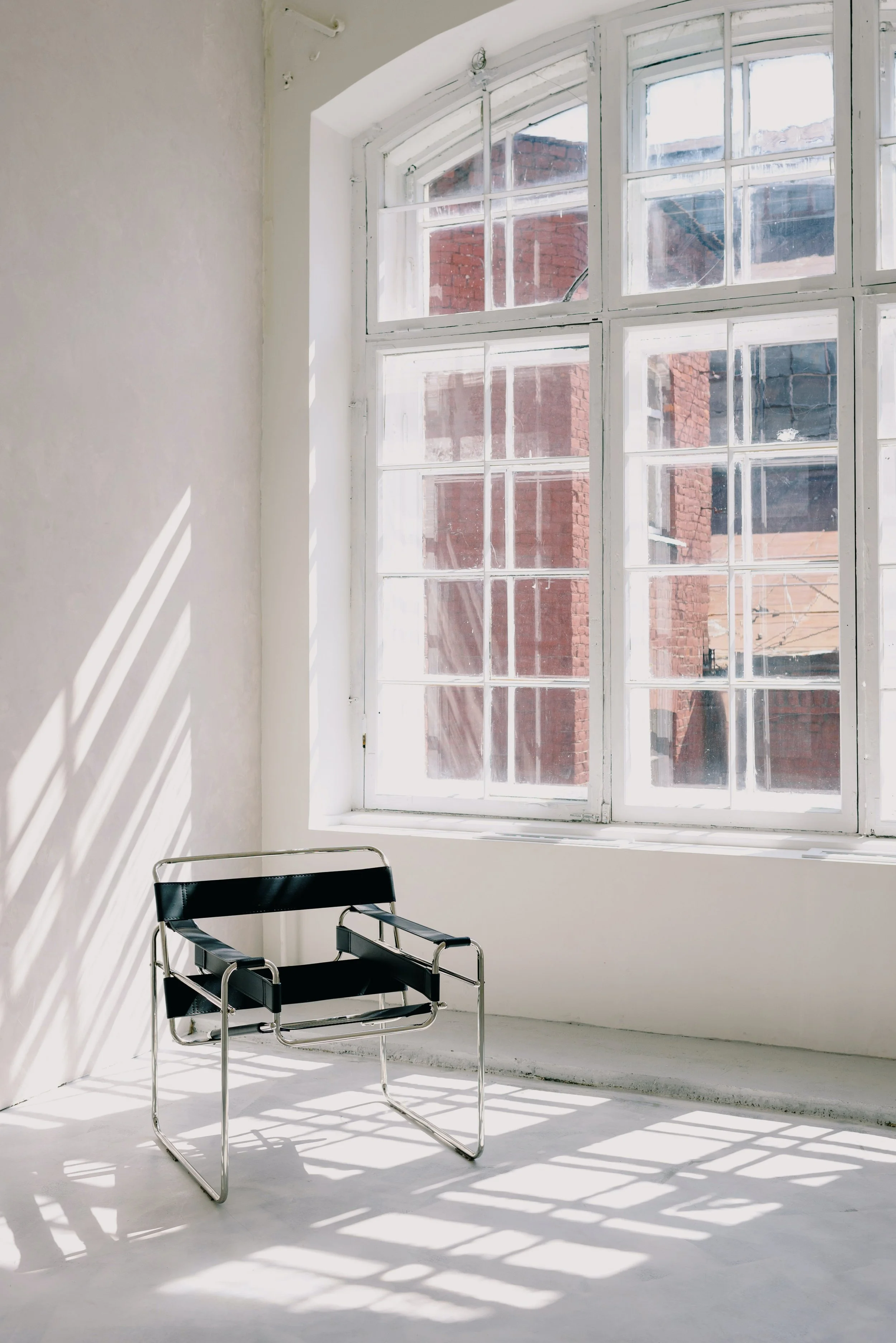 Modern chair in front of large window with brick building view