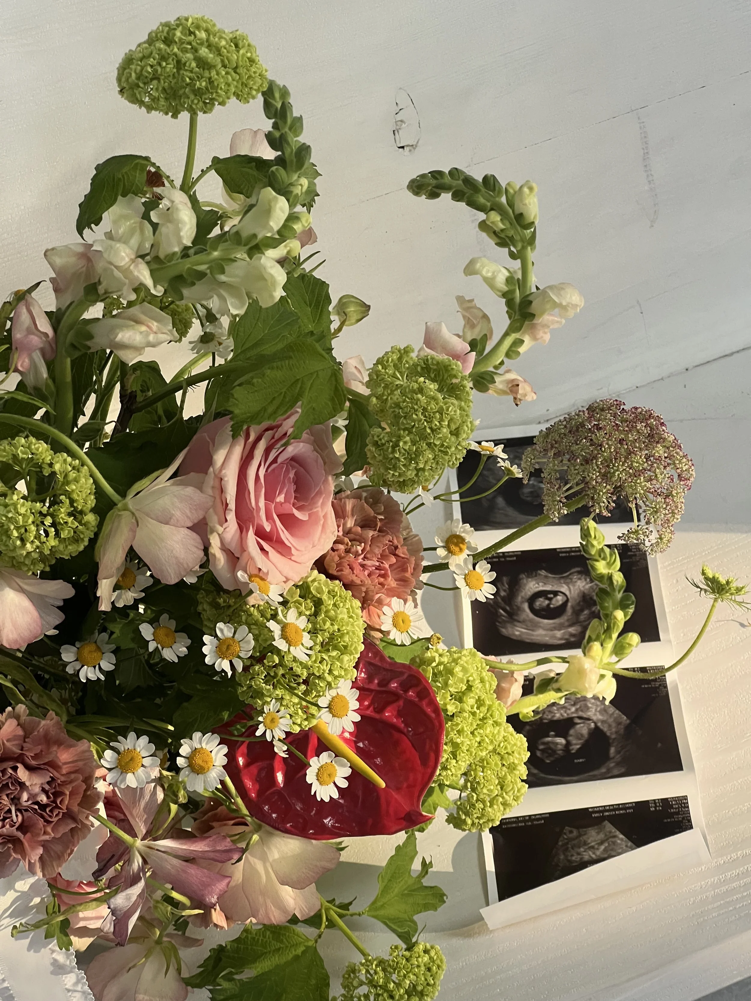 A bouquet of mixed flowers, including roses, daisies, and green hydrangeas, next to ultrasound images on a white background.