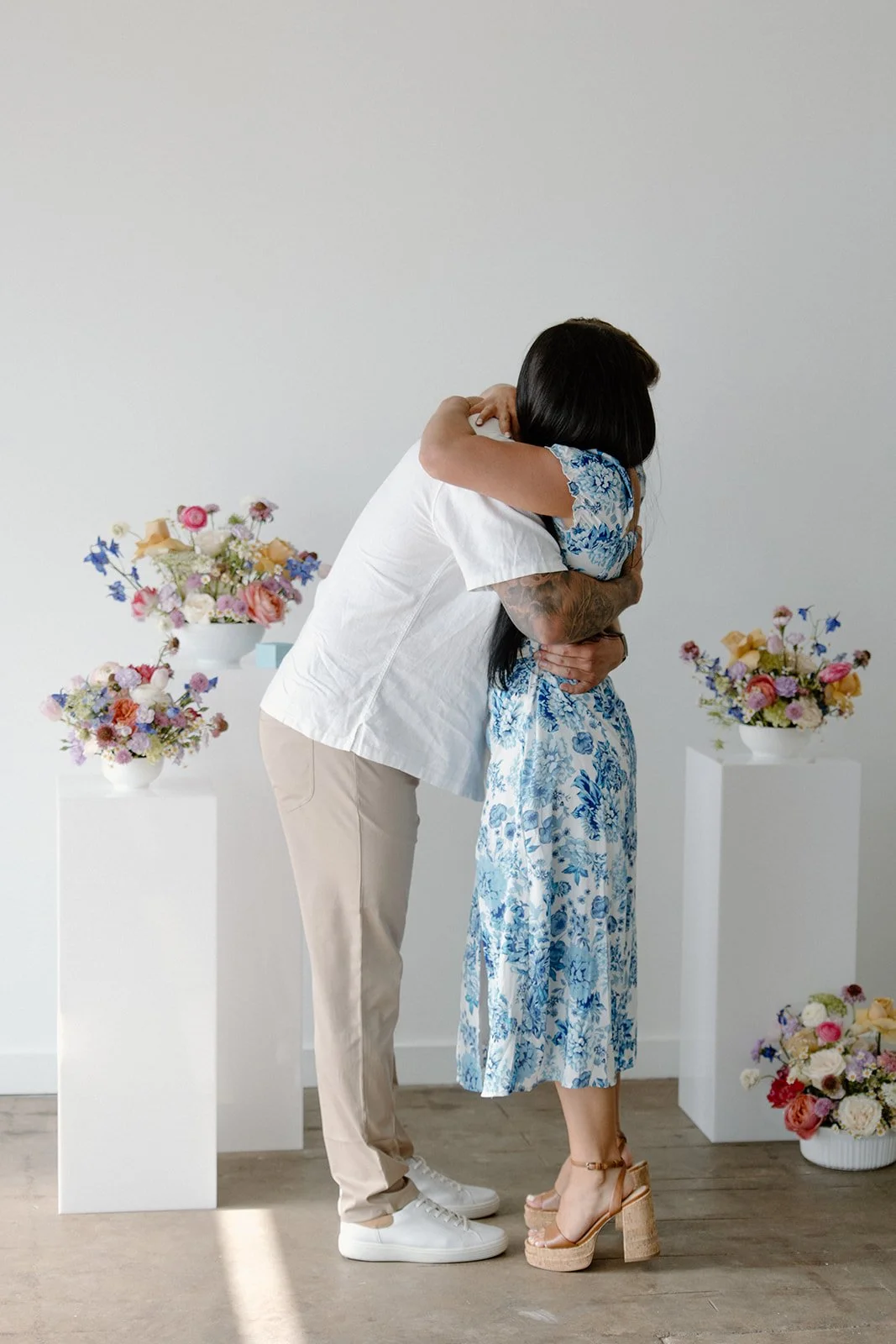 A couple hugging in a room decorated with floral arrangements.