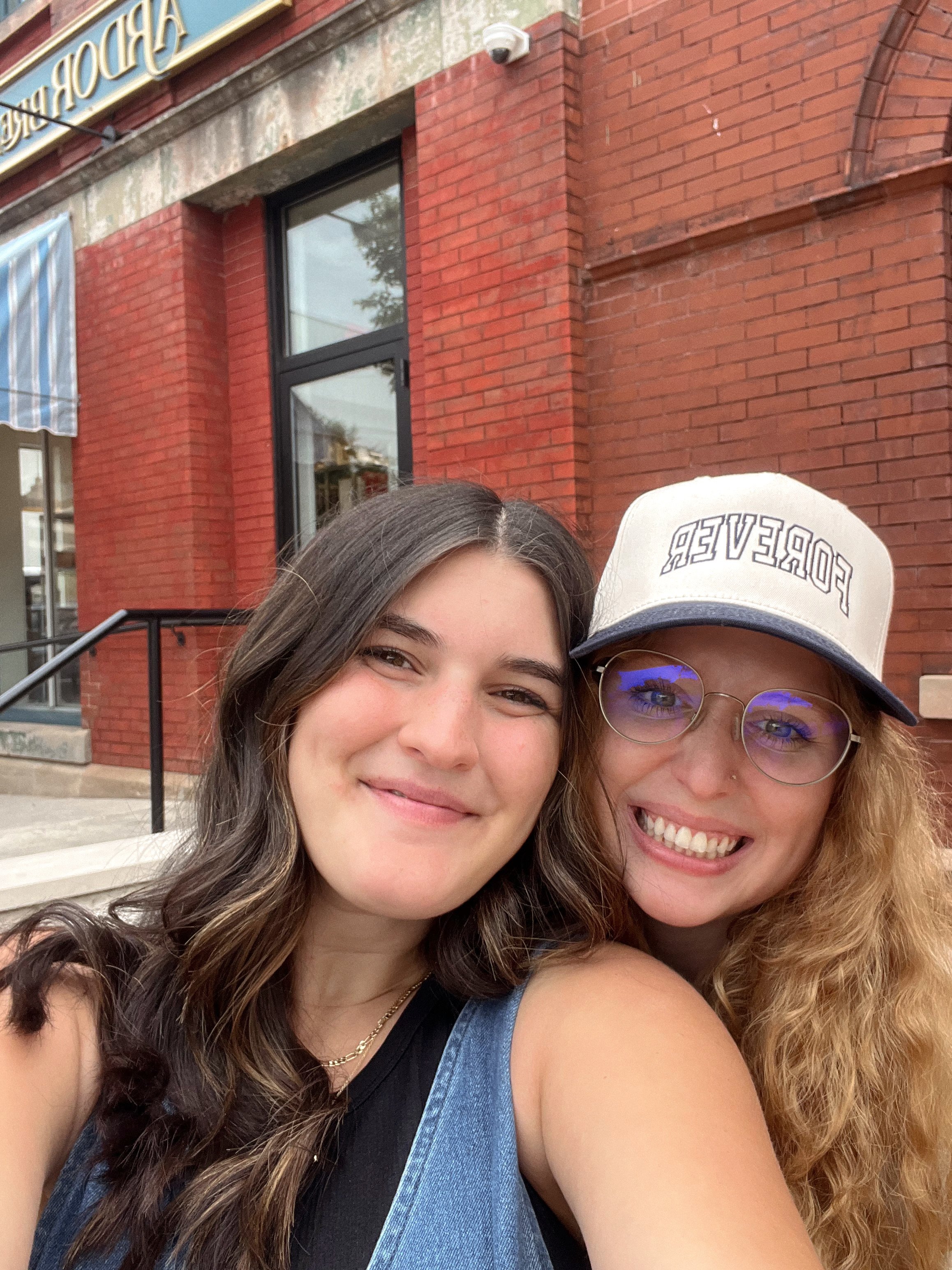 Two women smiling in front of a red brick building.