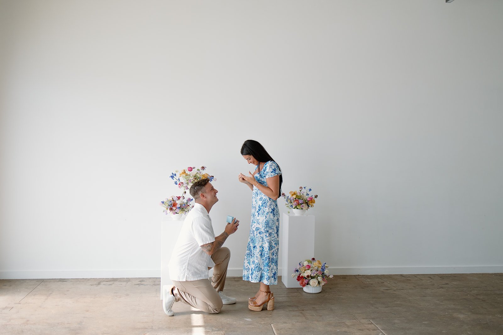 Man kneeling with ring proposing to woman in floral dress