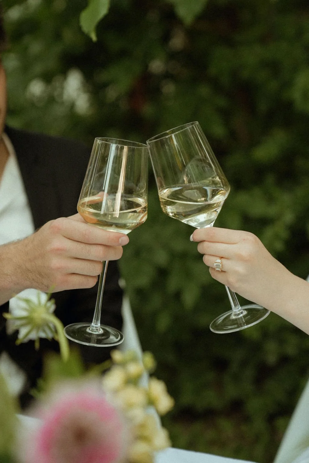 A couple toasting with wine glasses outdoors.