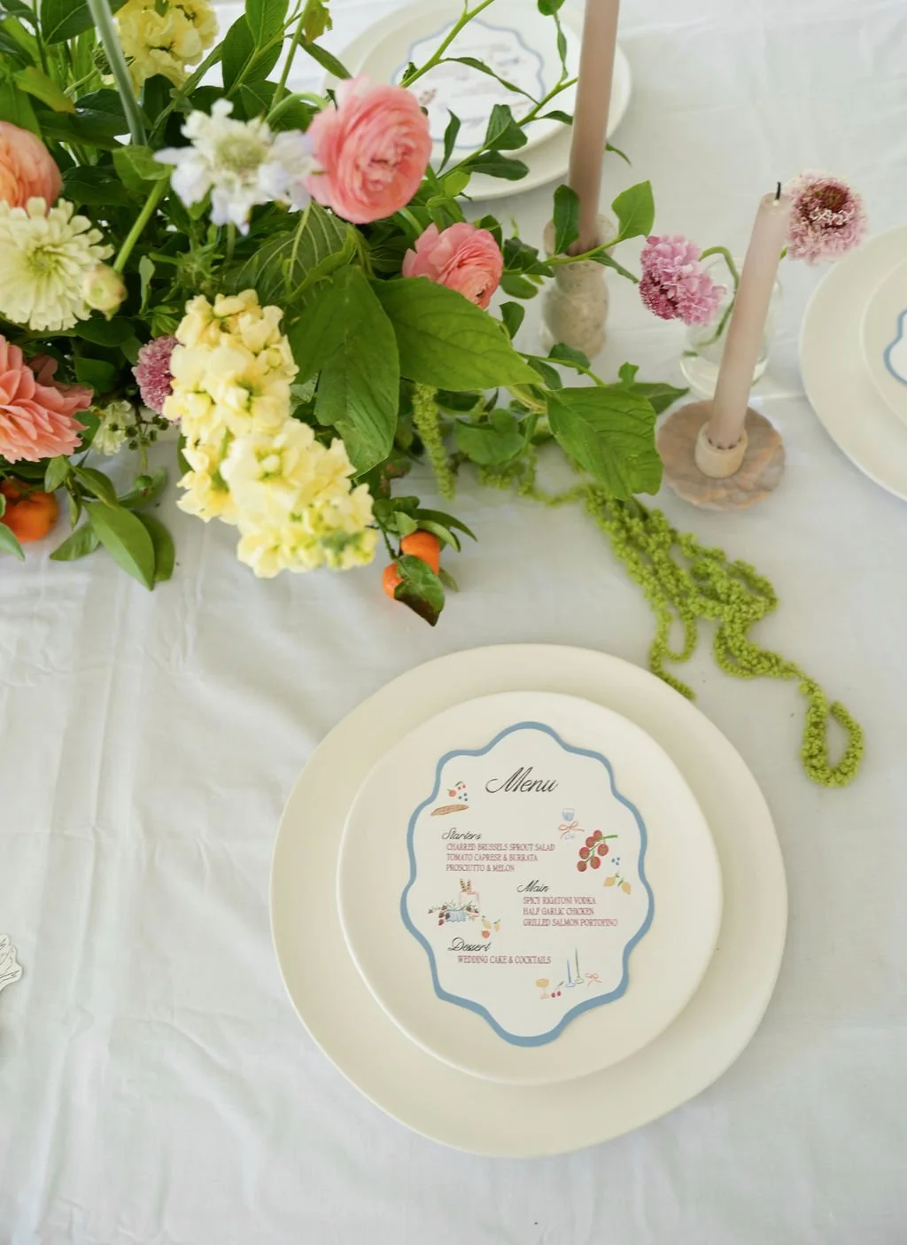 Elegant table setting with floral centerpiece, candles, and a menu on a plate.