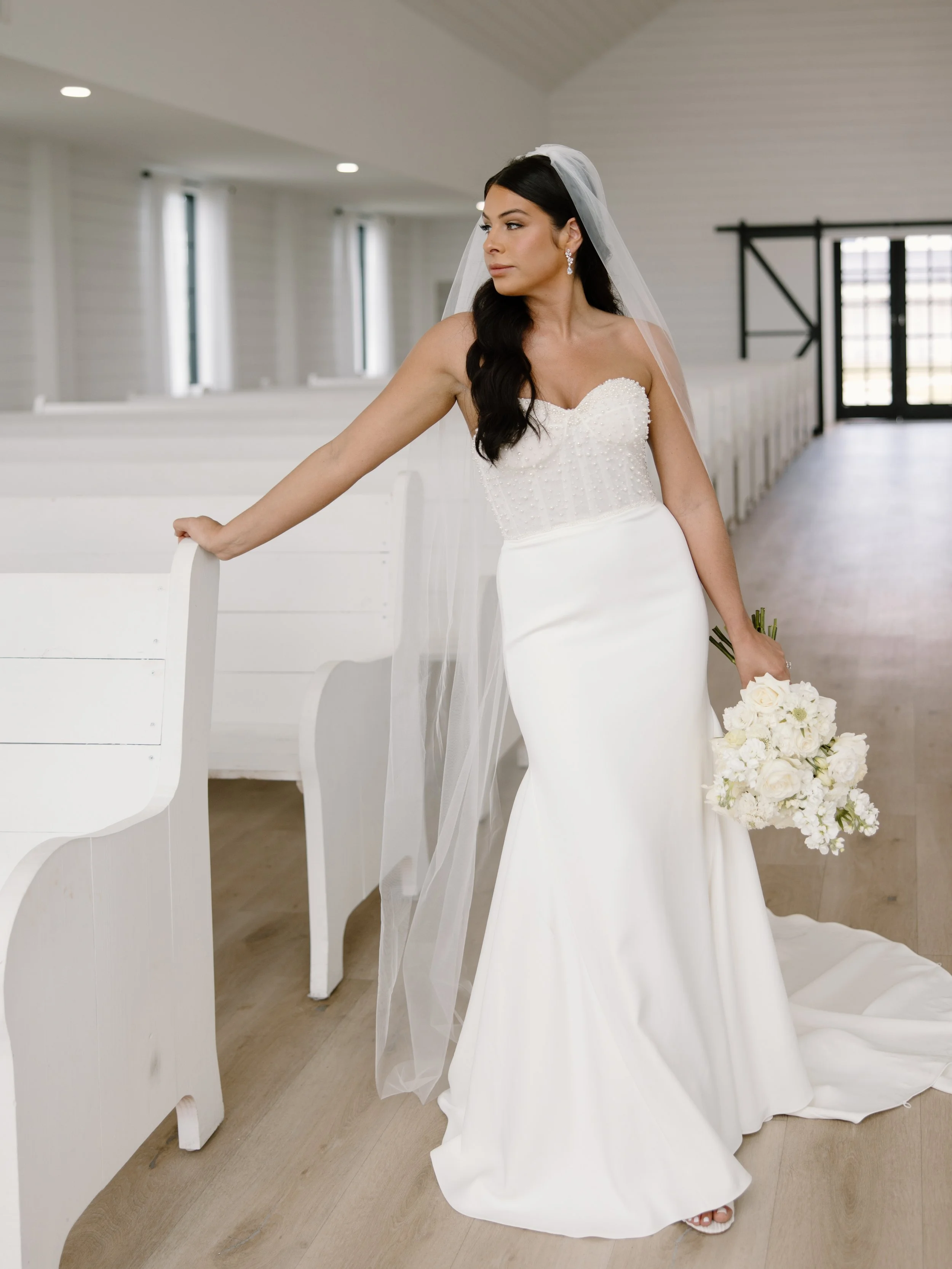 Bride in white dress holding bouquet in a chapel