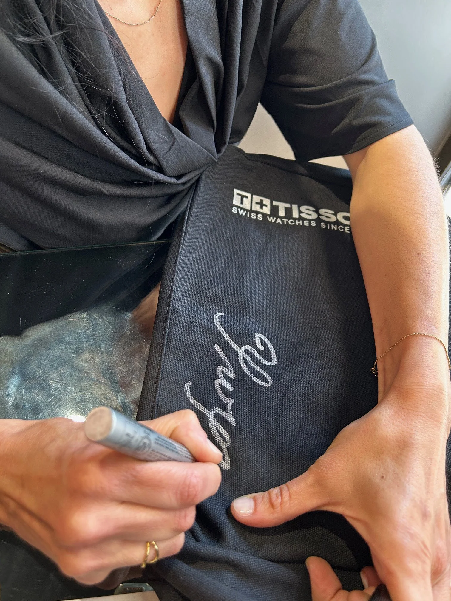 Calligrapher Yianna Korre writing a name in calligraphy on a Tissot tote bag at Athens store