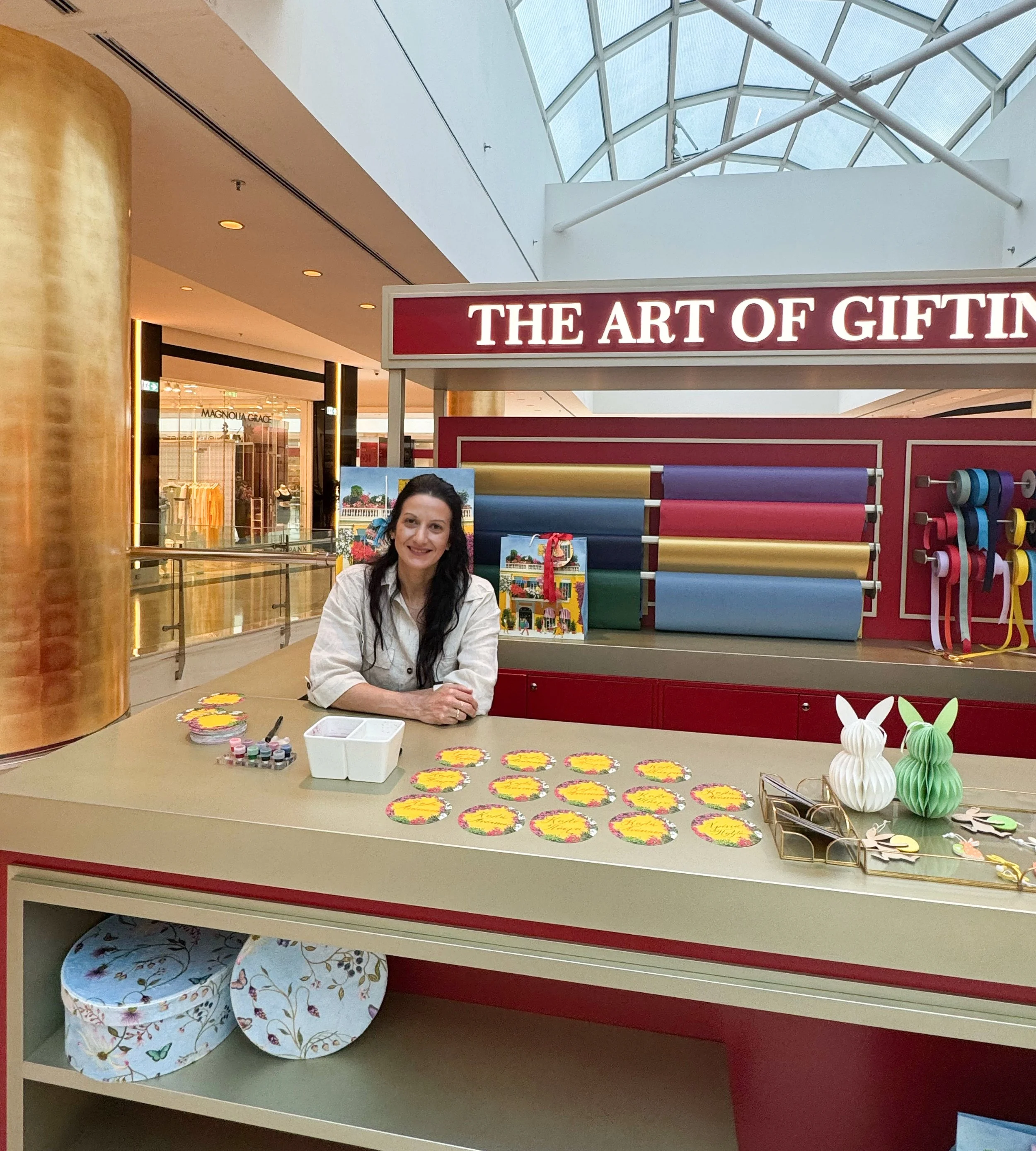 Calligrapher Yianna Korre sitting on Gifting Station at Golden Hall, Athens for an Easter activation
