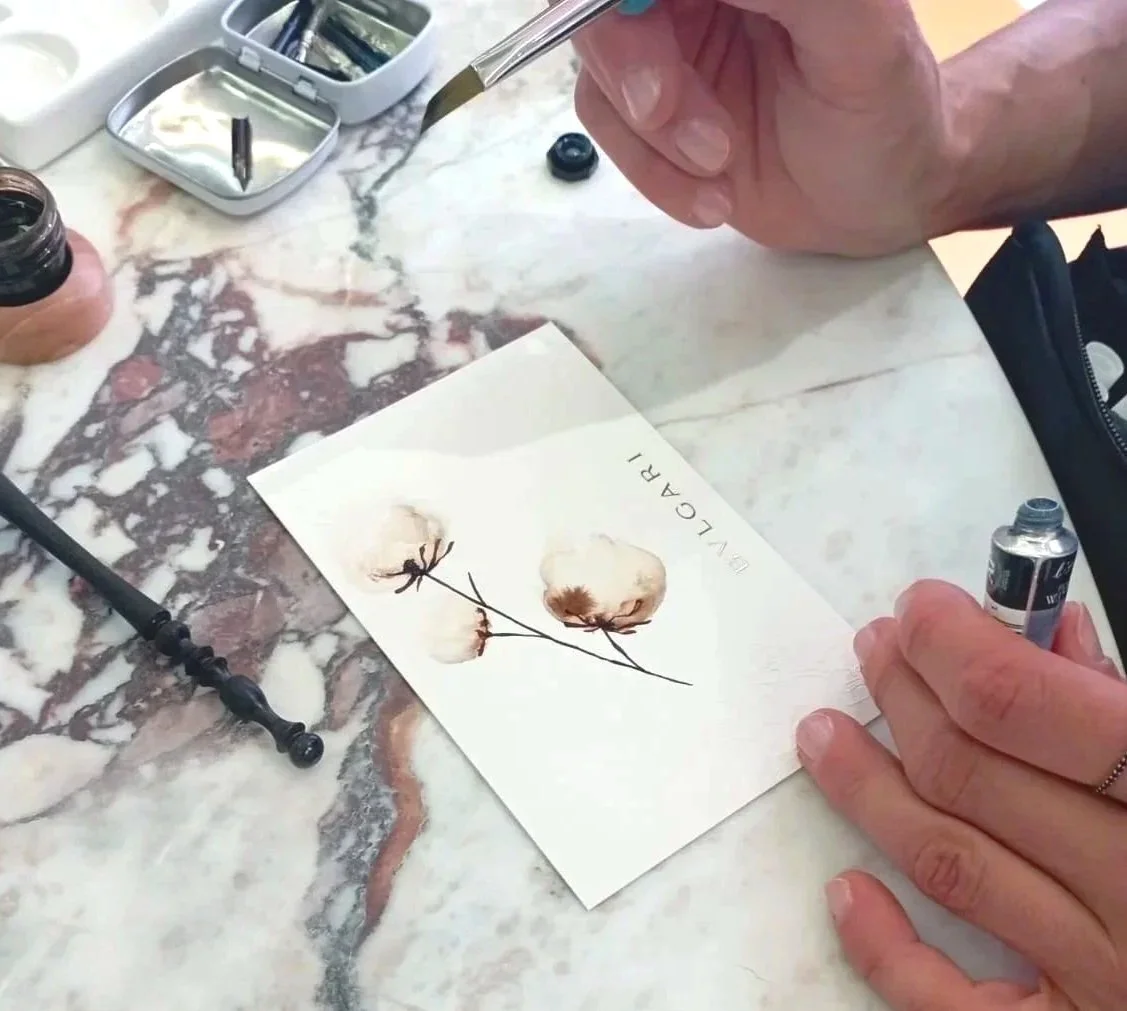 Yianna Korre calligrapher and painter, painting cotton flowers in watercolour for Bulgari brand activation at Athens International Airport