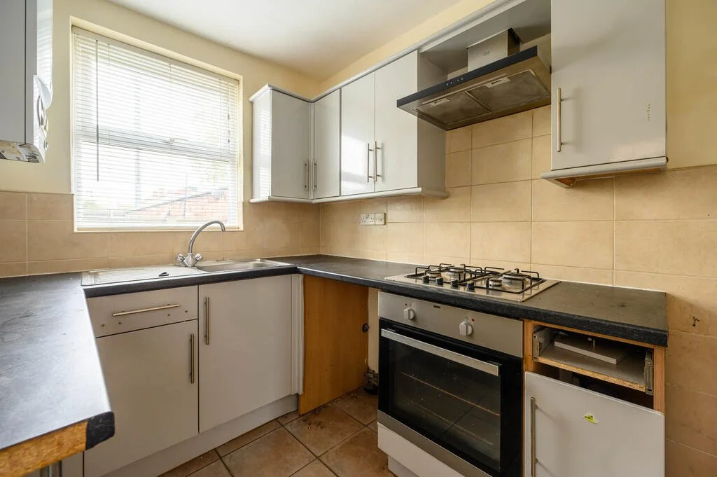 Merritt Estates. Small kitchen with white cabinets, black countertops, a stove with four burners, a built-in oven, and a window above the sink.