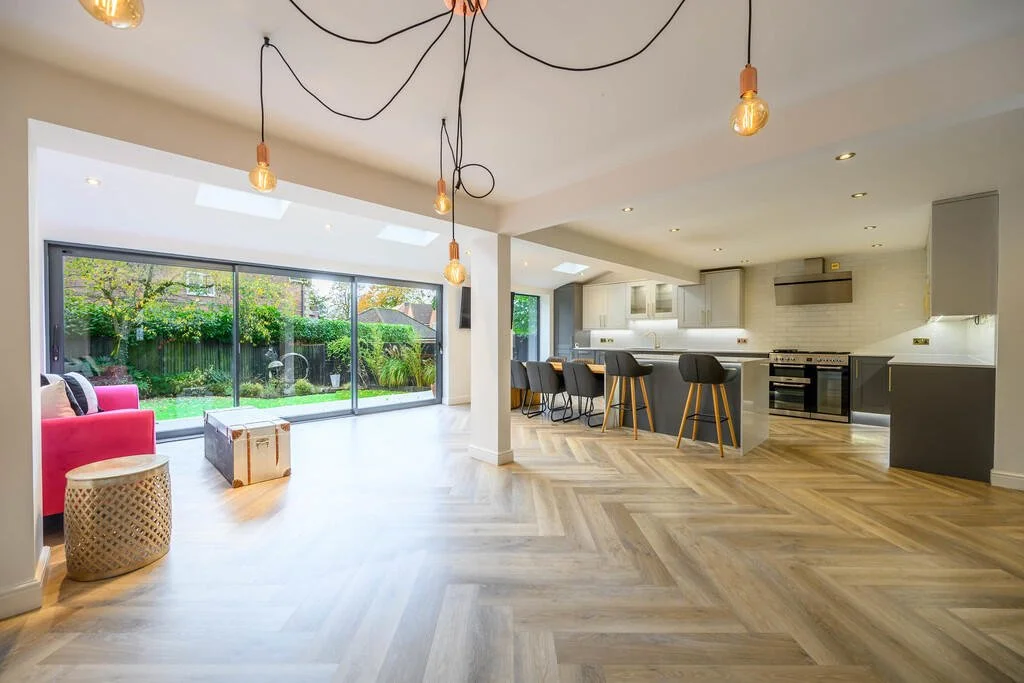 Merritt Estates. Open-concept living room and kitchen with large sliding glass doors, hardwood floors, modern furniture, and pendant lighting.