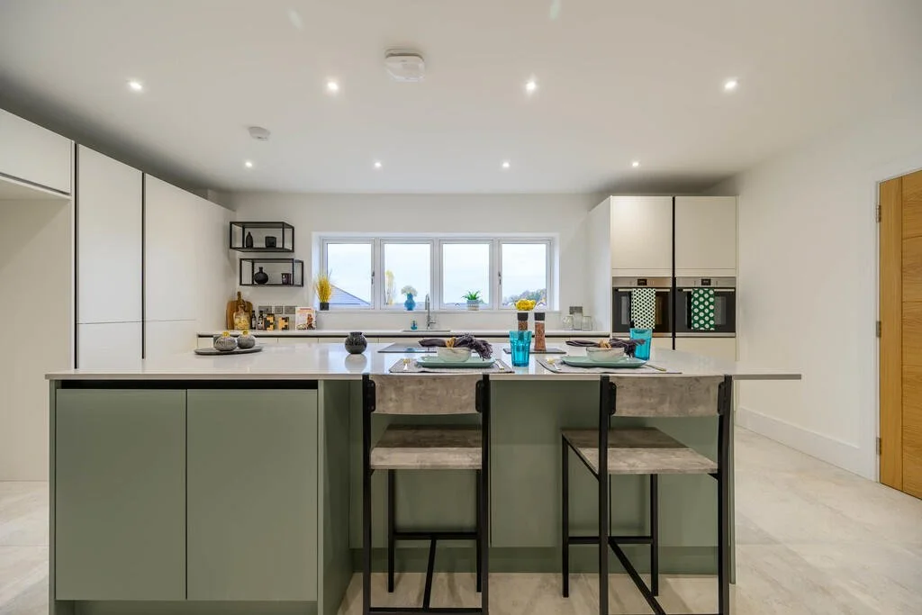 Merritt Estates. Modern kitchen with white cabinetry, a central island with barstools, a window above the sink, and decorative items on the countertops