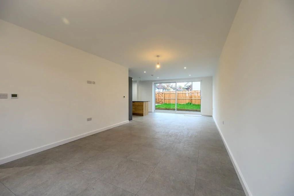 Merritt Estates. Empty living room with large sliding glass doors opening to a backyard with grass and a wooden fence.