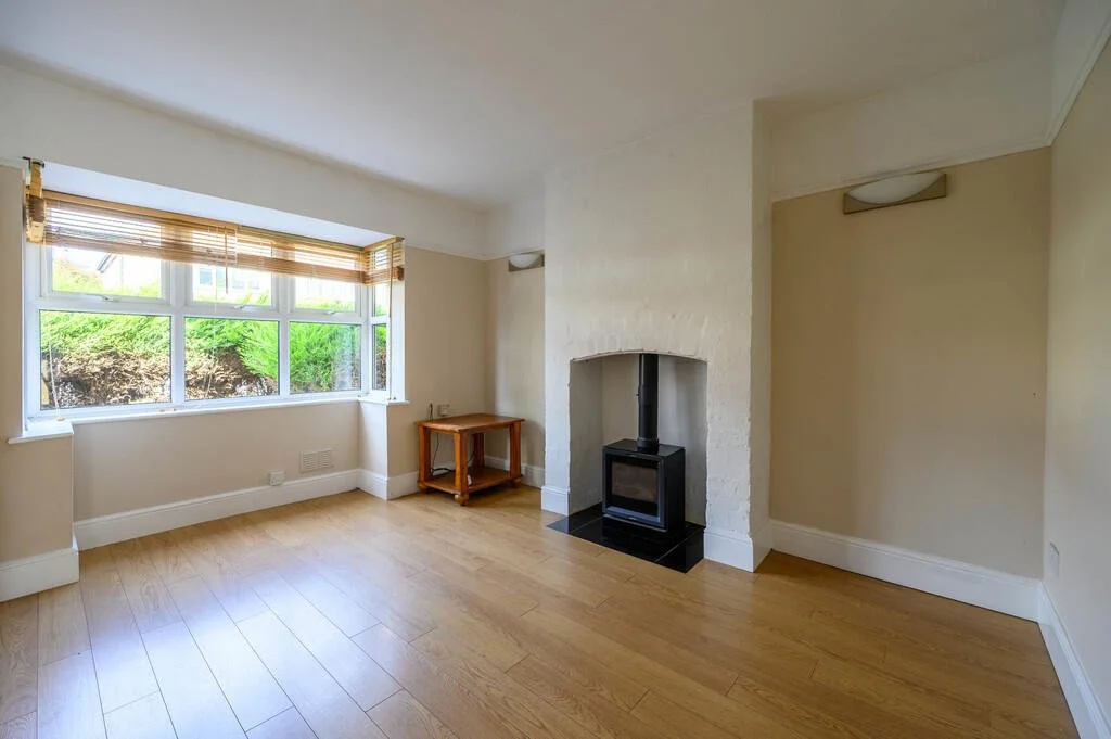 Merritt Estates. An empty living room with a large window, a wooden floor, and a small stove in the corner.