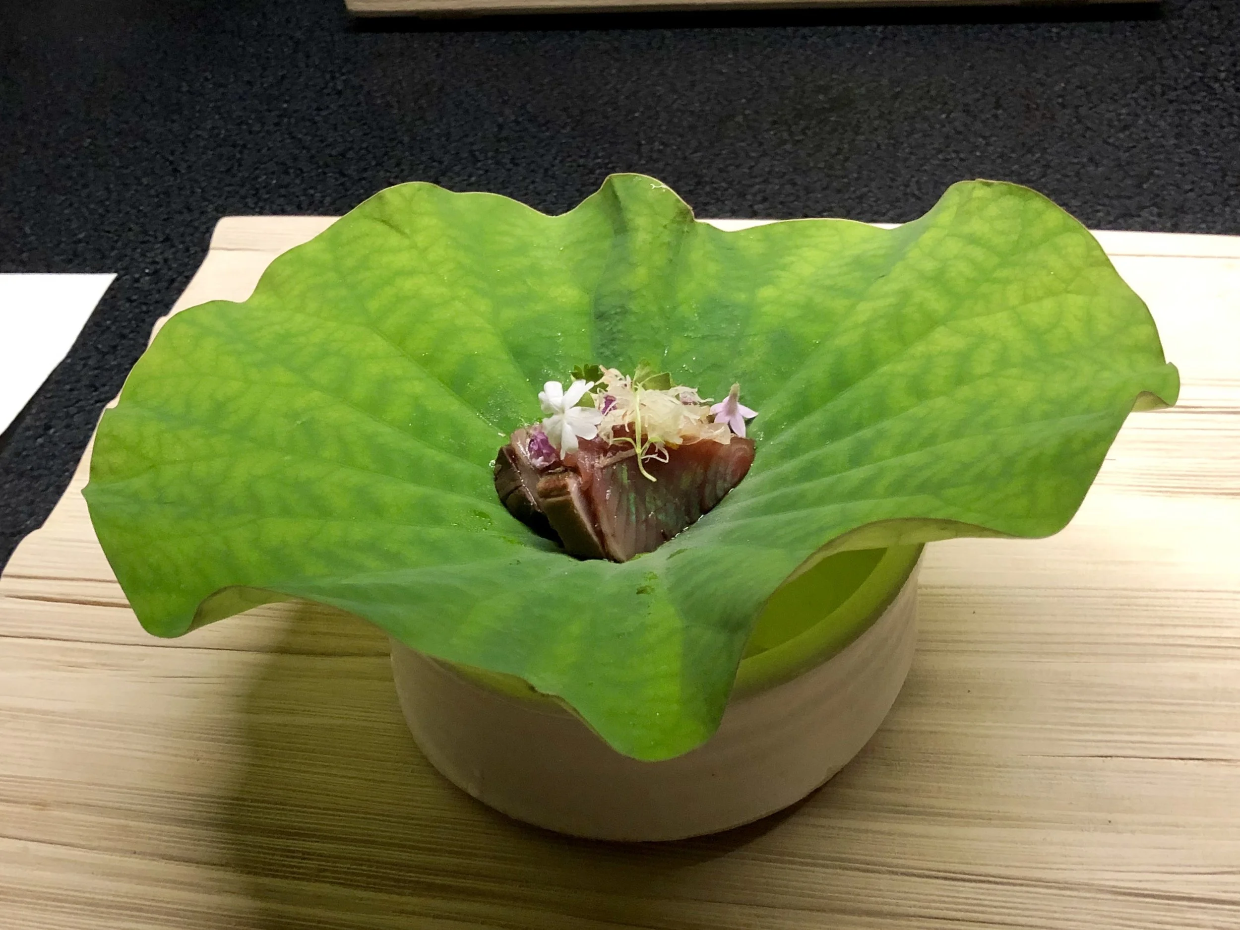Garnished tuna sashimi in a lotus leaf bowl, a dish from a Japanese meal photographed by Will.