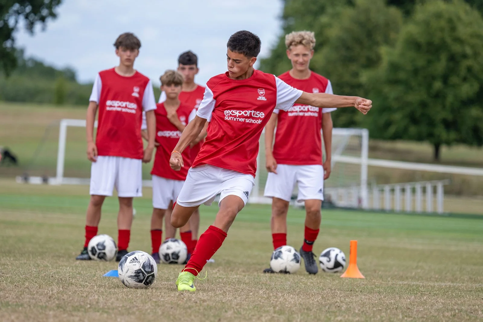 A player taking a shot at goal during football practice.