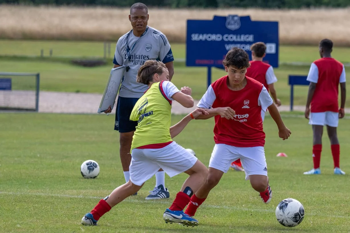 Two boys playing football at an Arsenal camp.