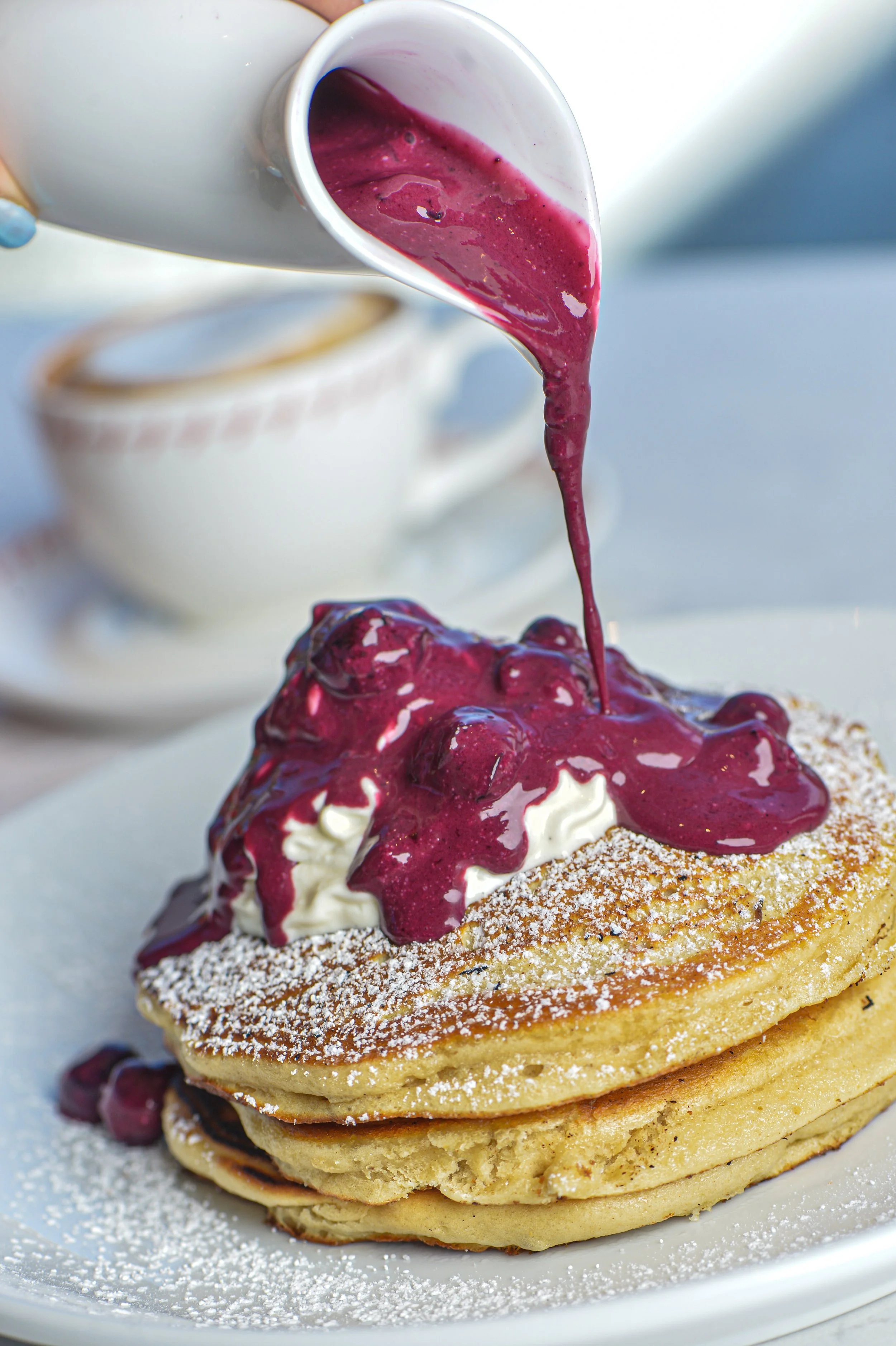 Pancakes with purple berry sauce and whipped cream