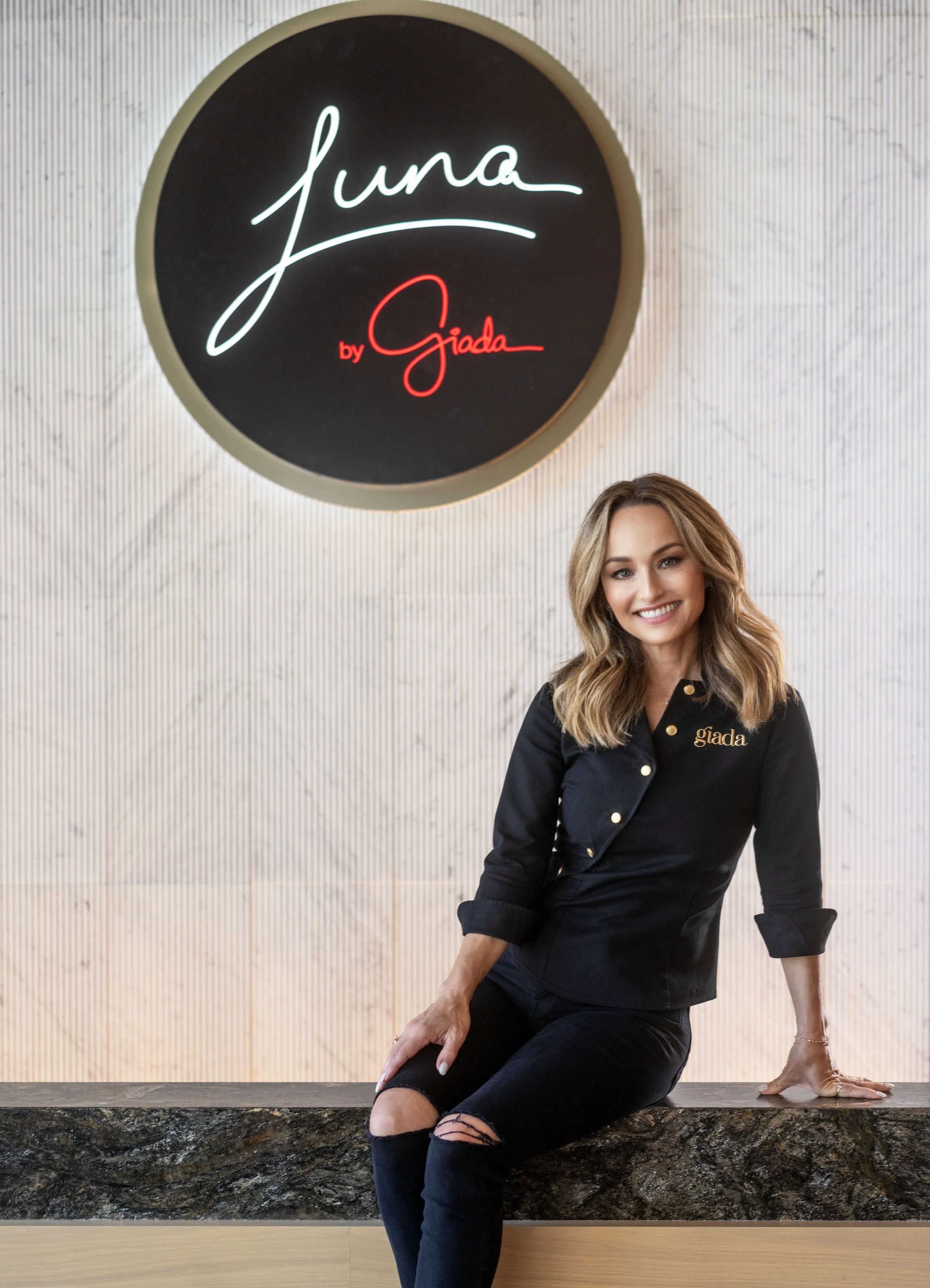 Person sitting under a sign reading 'Luna by Giada'