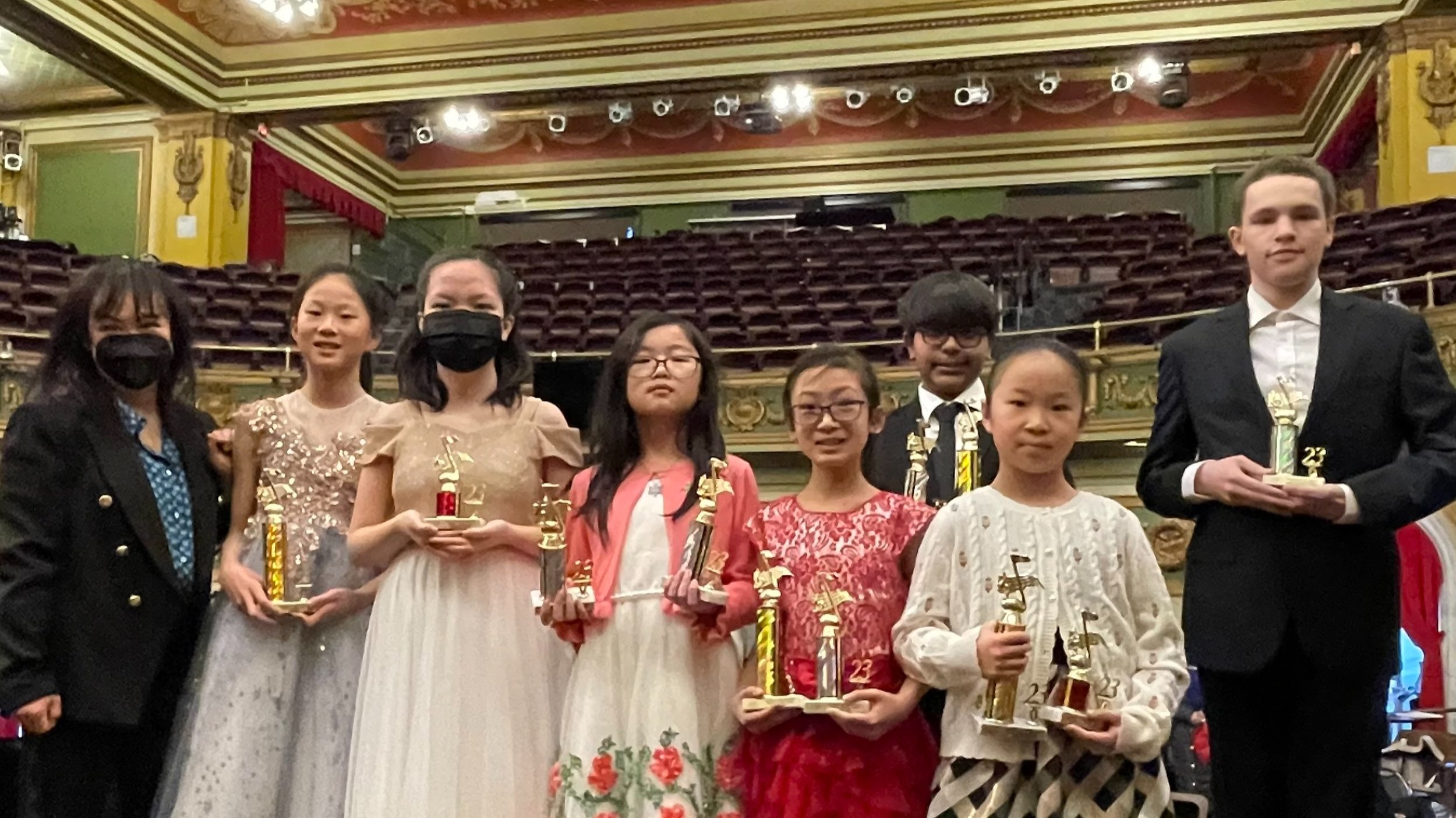 Piano students holding trophies after a competition, representing measurable progress and performance achievements.