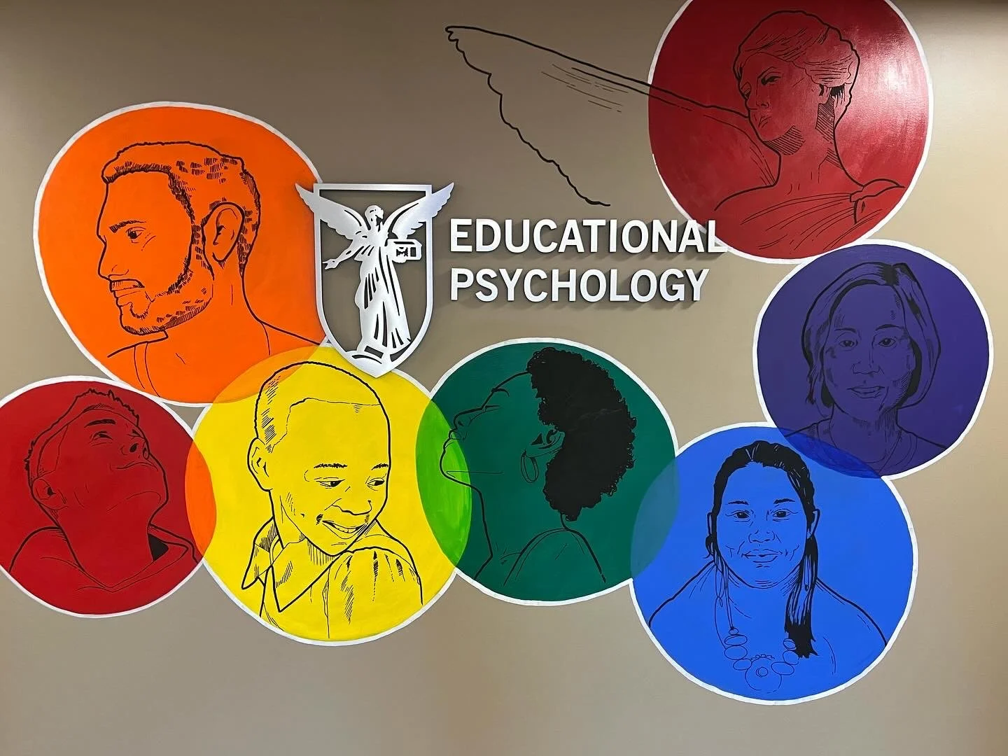 Wall decoration with colorful circles featuring line art portraits of diverse individuals, a shield with an angel, and the text 'Educational Psychology' in white letters.