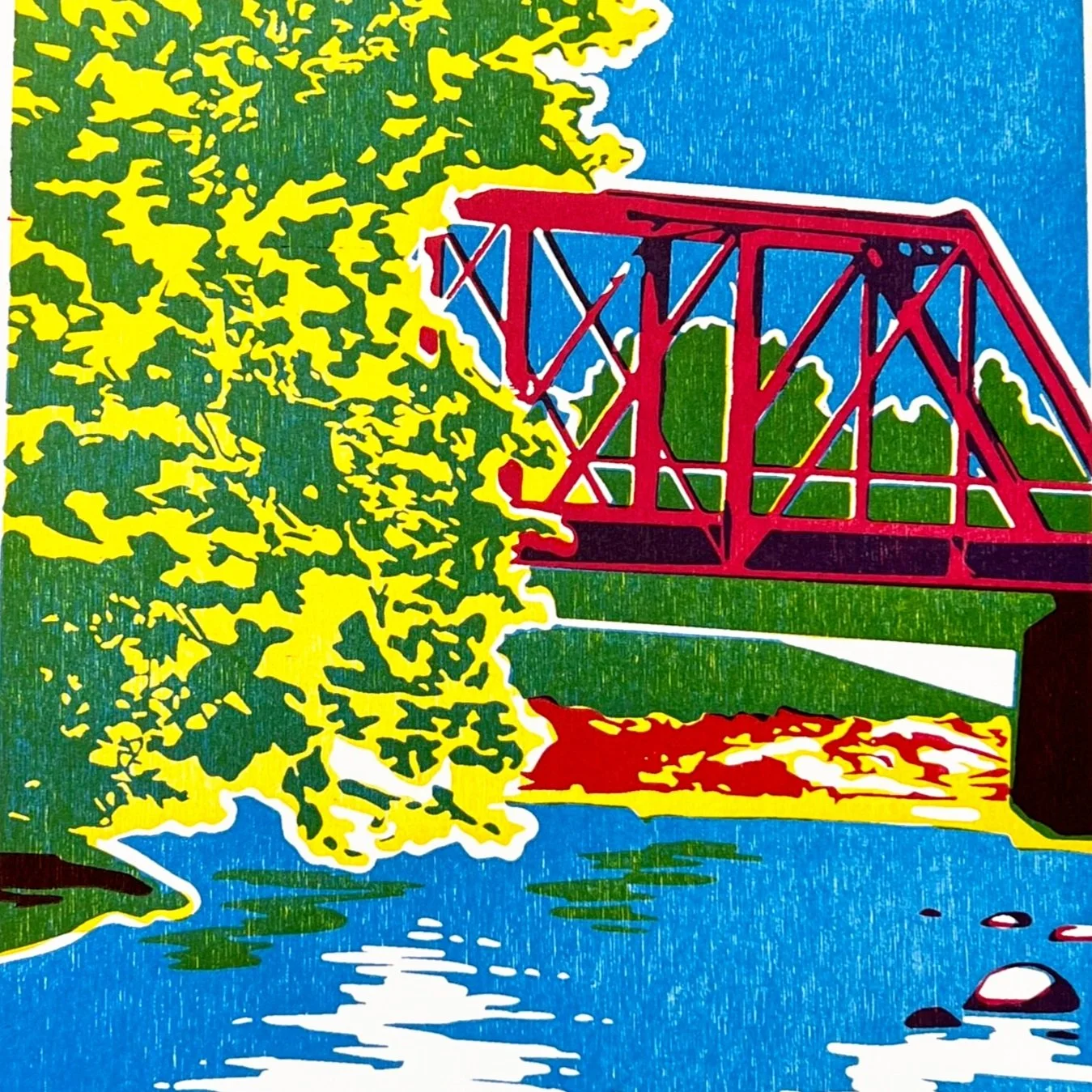 A colorful, stylized illustration of a red bridge over a river with yellow trees in the background and a blue sky made from three carved wood blocks.