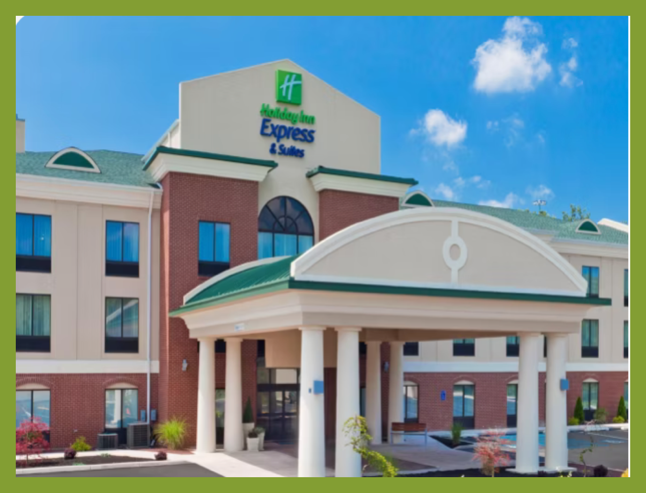 Exterior of a Holiday Inn Express & Suites hotel under a blue sky with a few clouds.