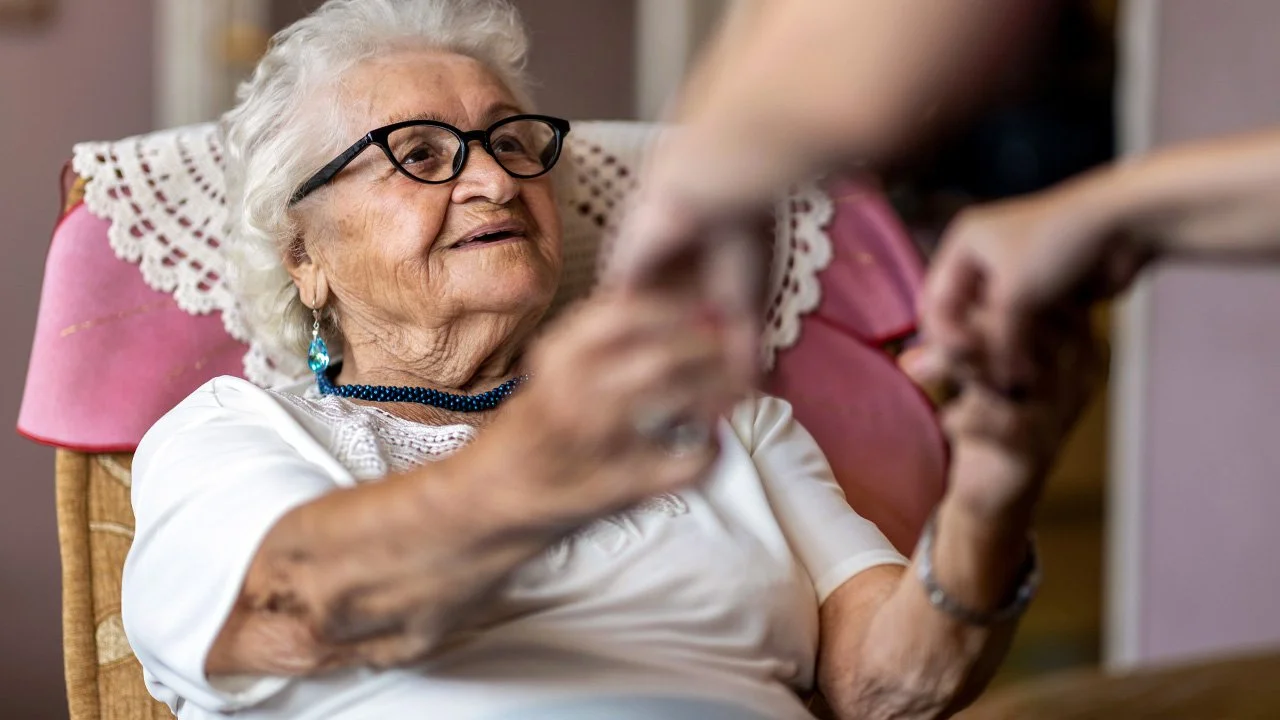 Female-home-carer-supporting-old-woman-to-stand-up-from-the-armchair-at-care-home_1280X720.jpg