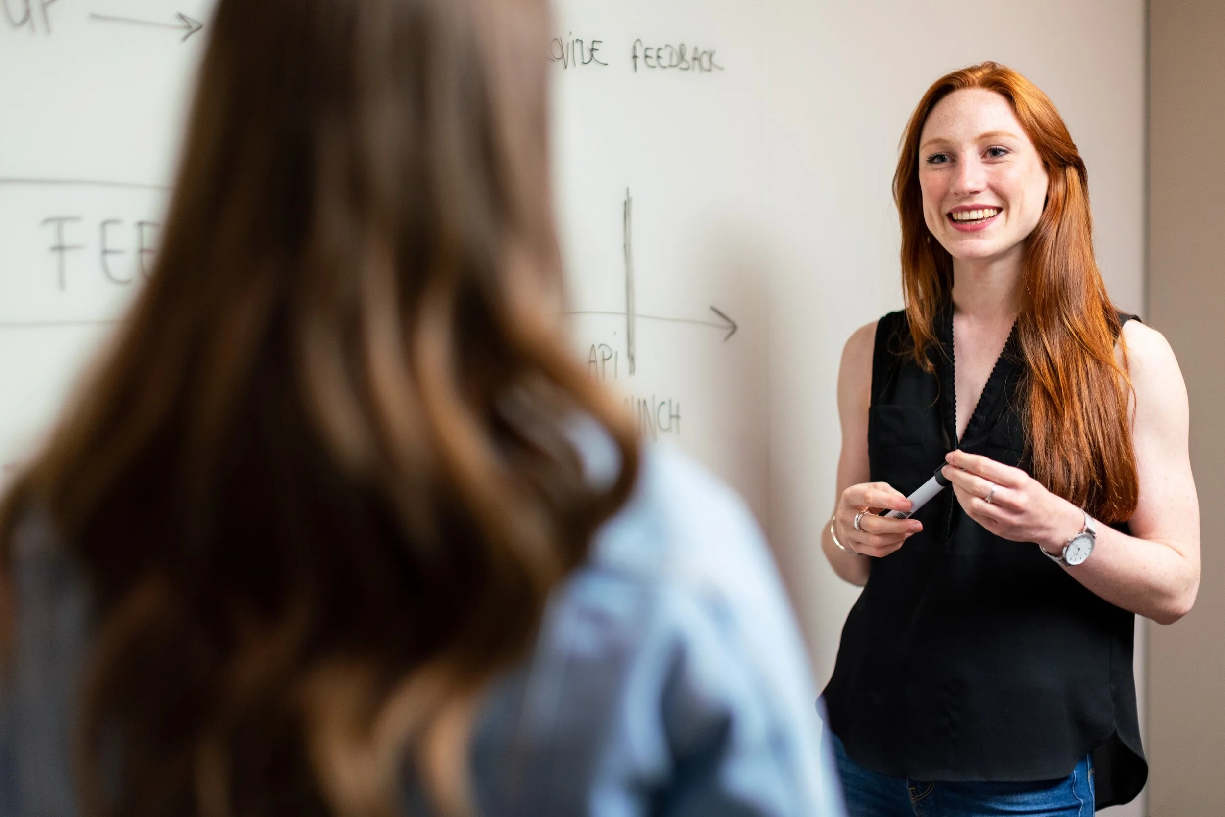 woman smiling and looking at another woman with her back to the camera