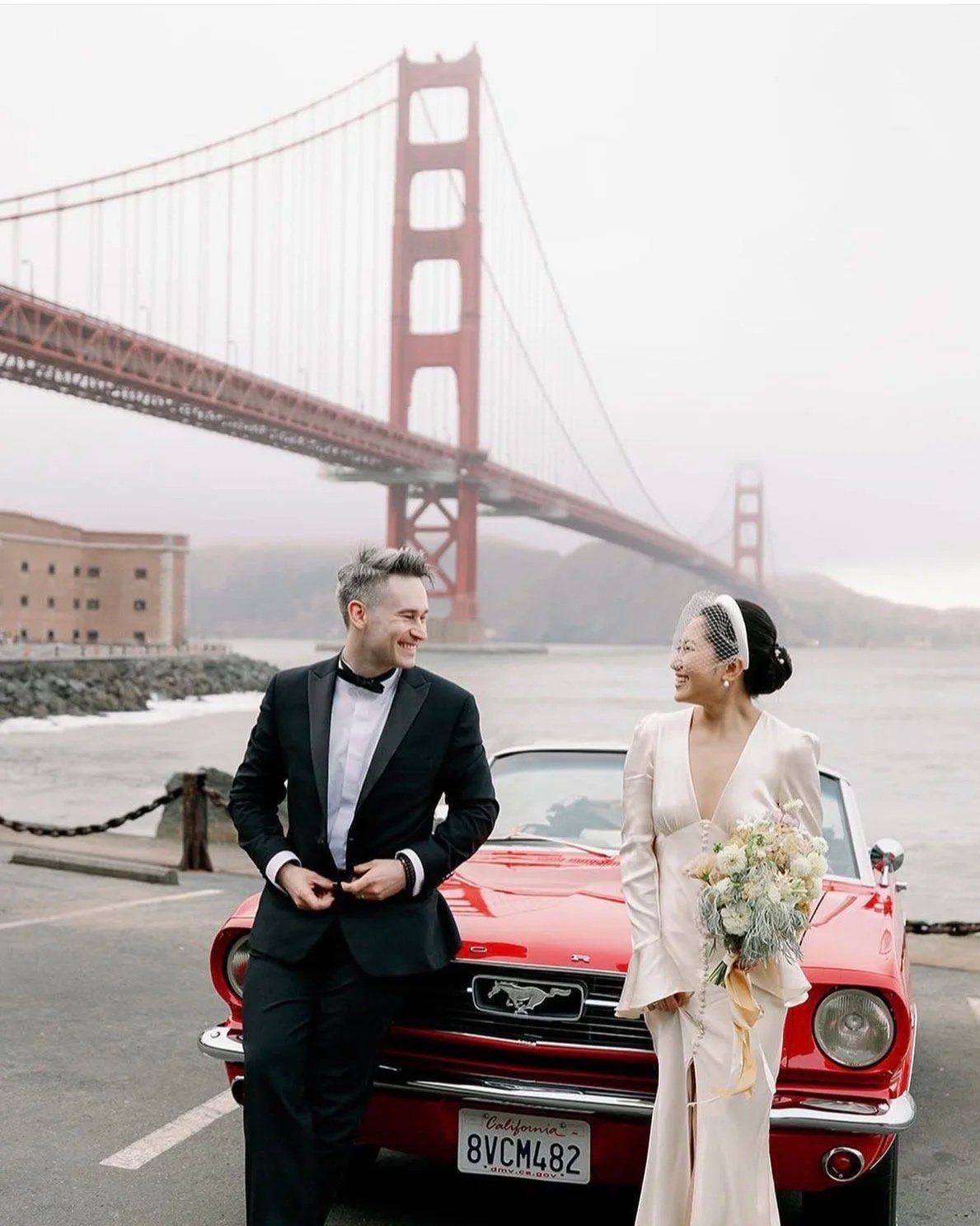 Vintage style elopement with bride and groom in front of the Golden Gate Bridge  next to the red ford mustang