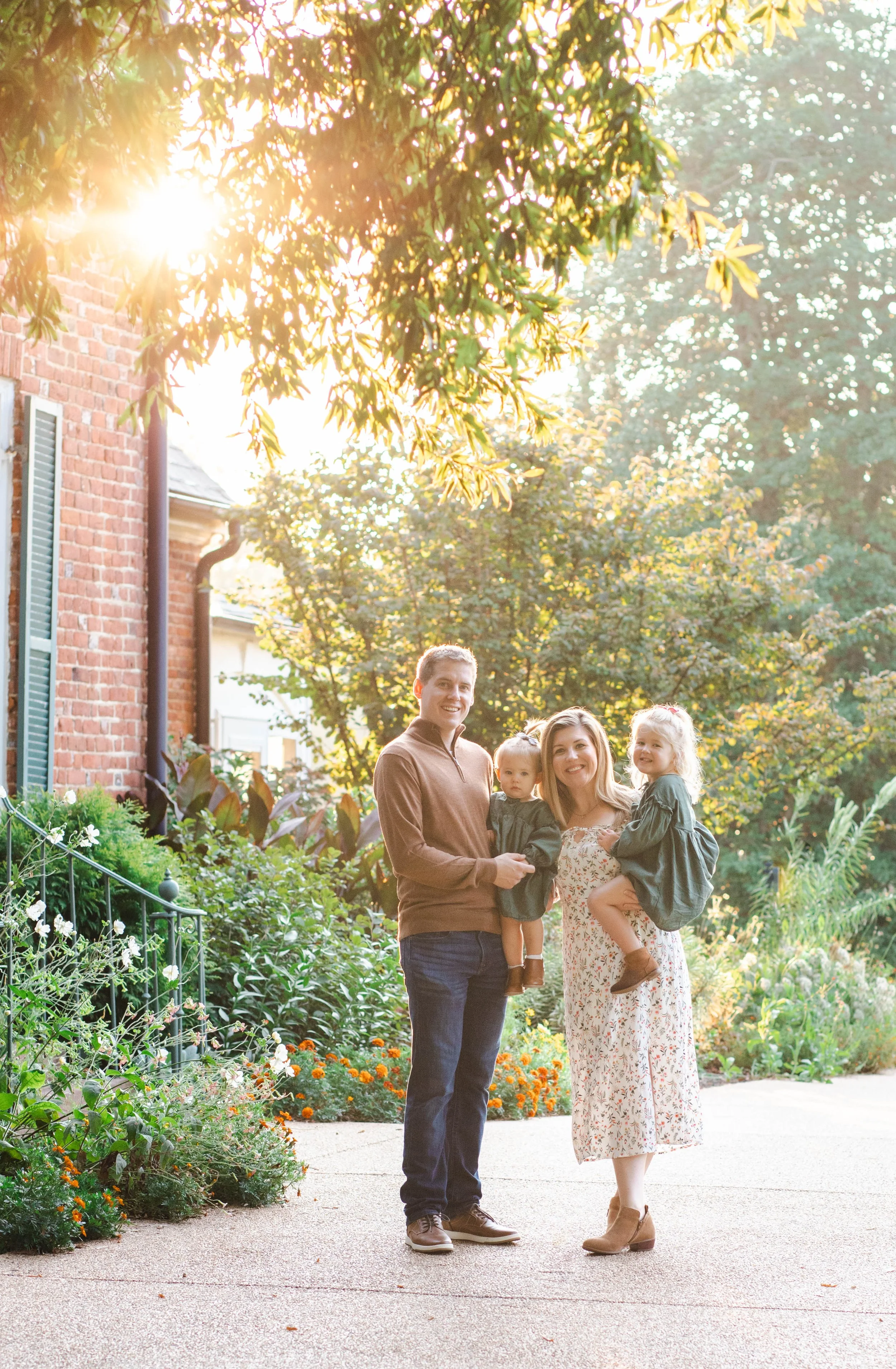 Family of four smiling together in a sunlit garden during a golden hour family photo session in Northern Virginia — Amanda Kahnell Photography