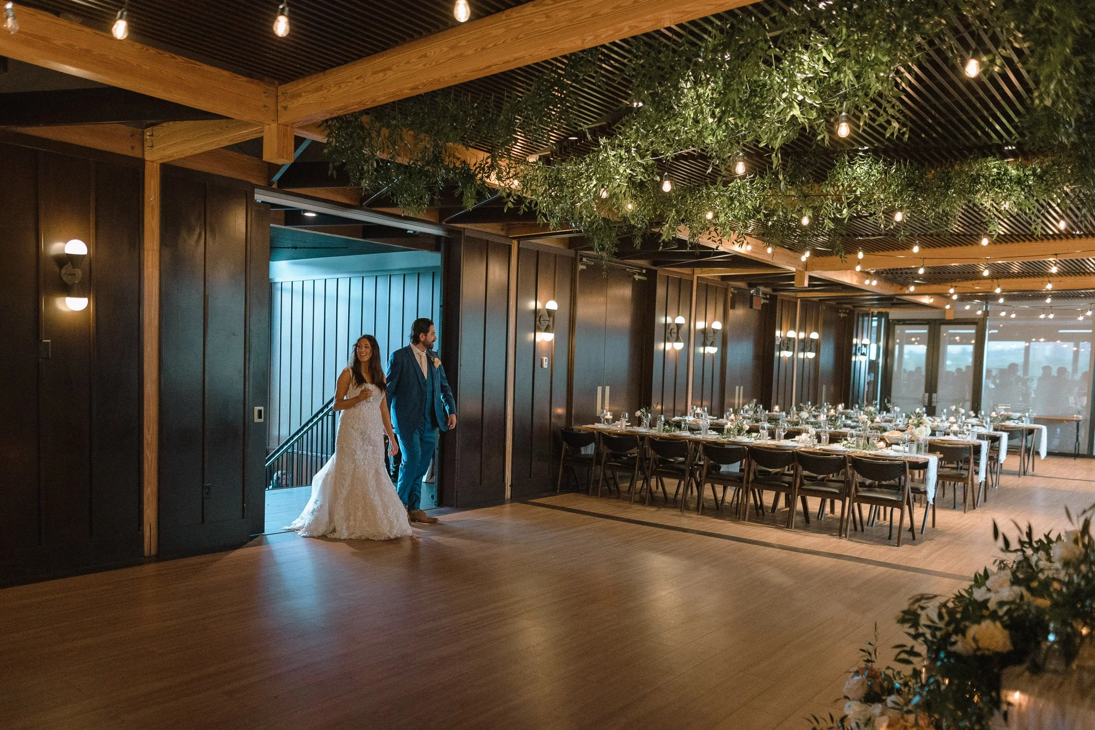 Bride and groom entering wedding  first look at reception space surrounded by greenery