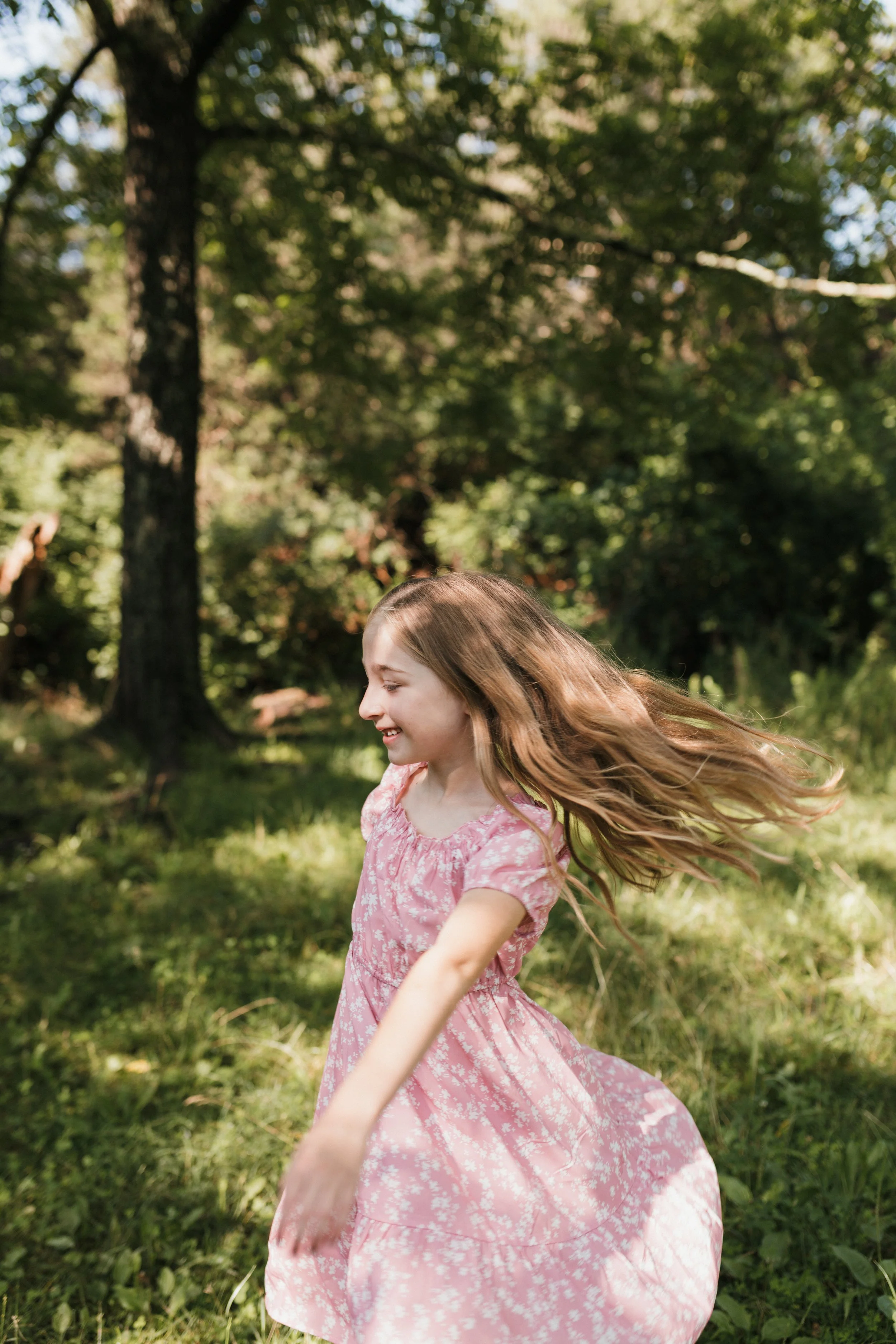 Child spinning and playing in the grass during a relaxed family photography session at Manassas National Battlefield Park in Northern Virginia.