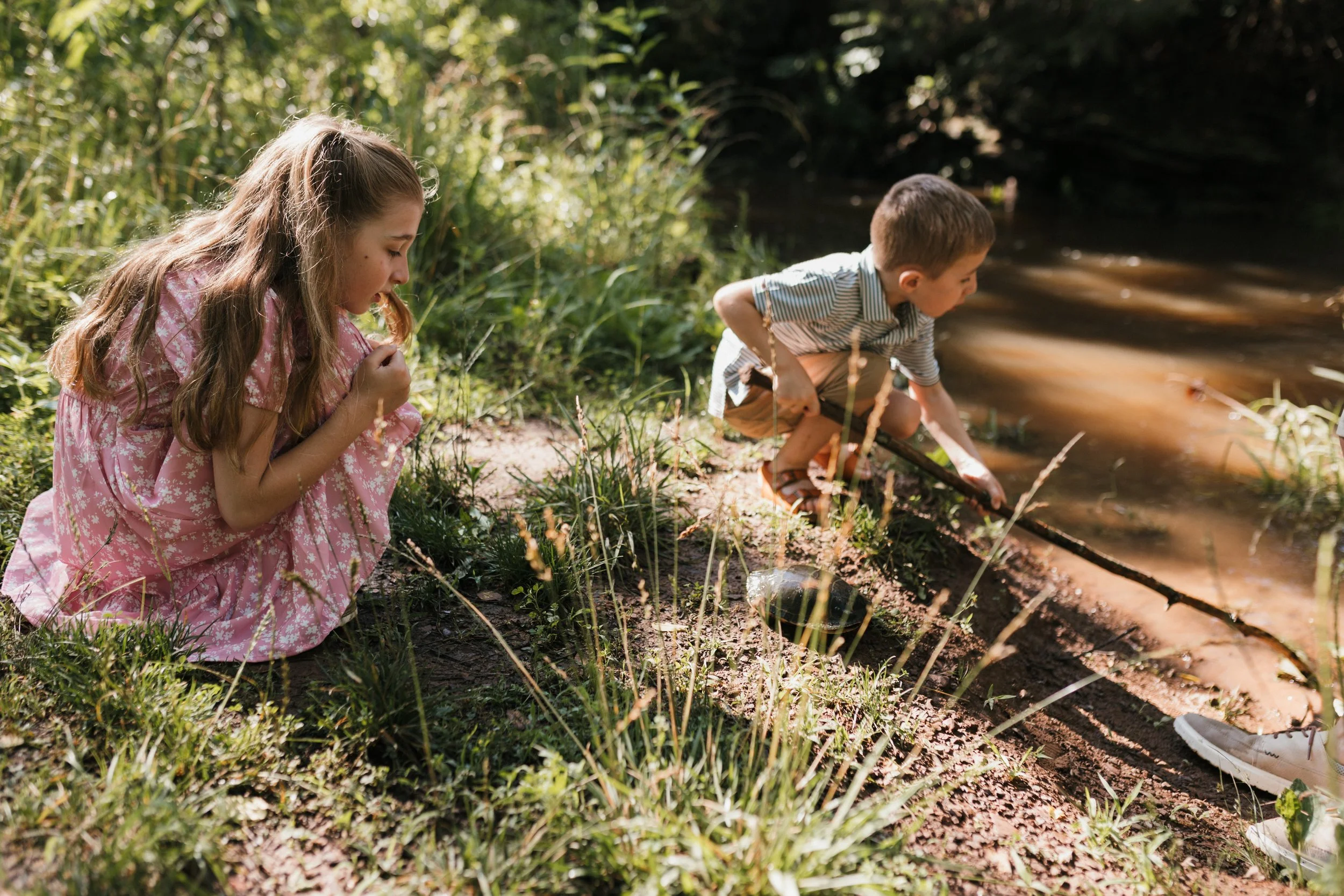 Children exploring a creek together at Manassas National Battlefield Park during a relaxed family photography session.