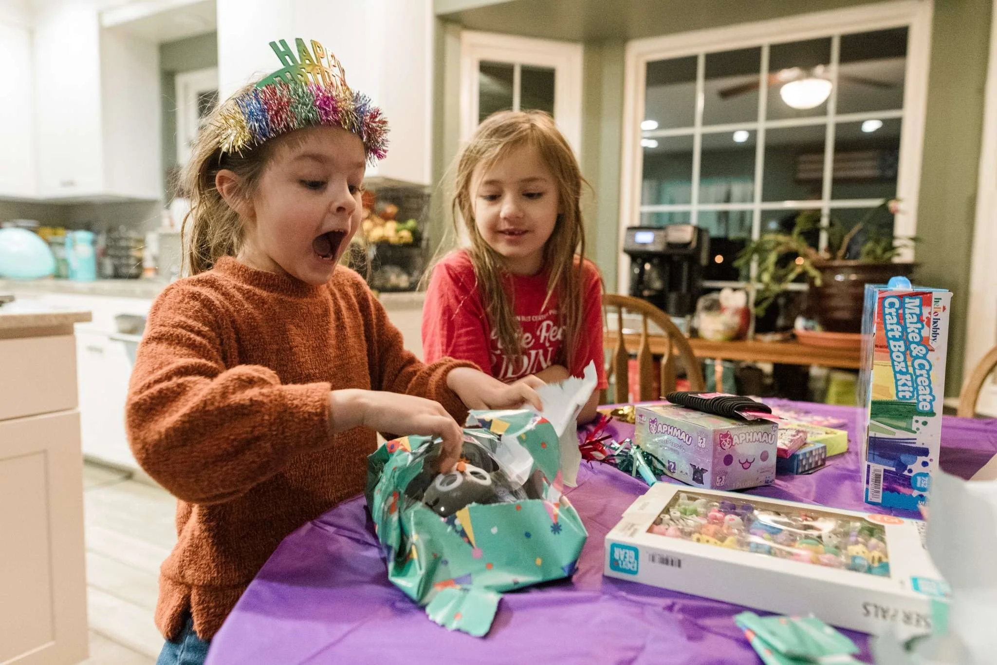Child opening a birthday gift during an in-home documentary family photography session in Northern Virginia