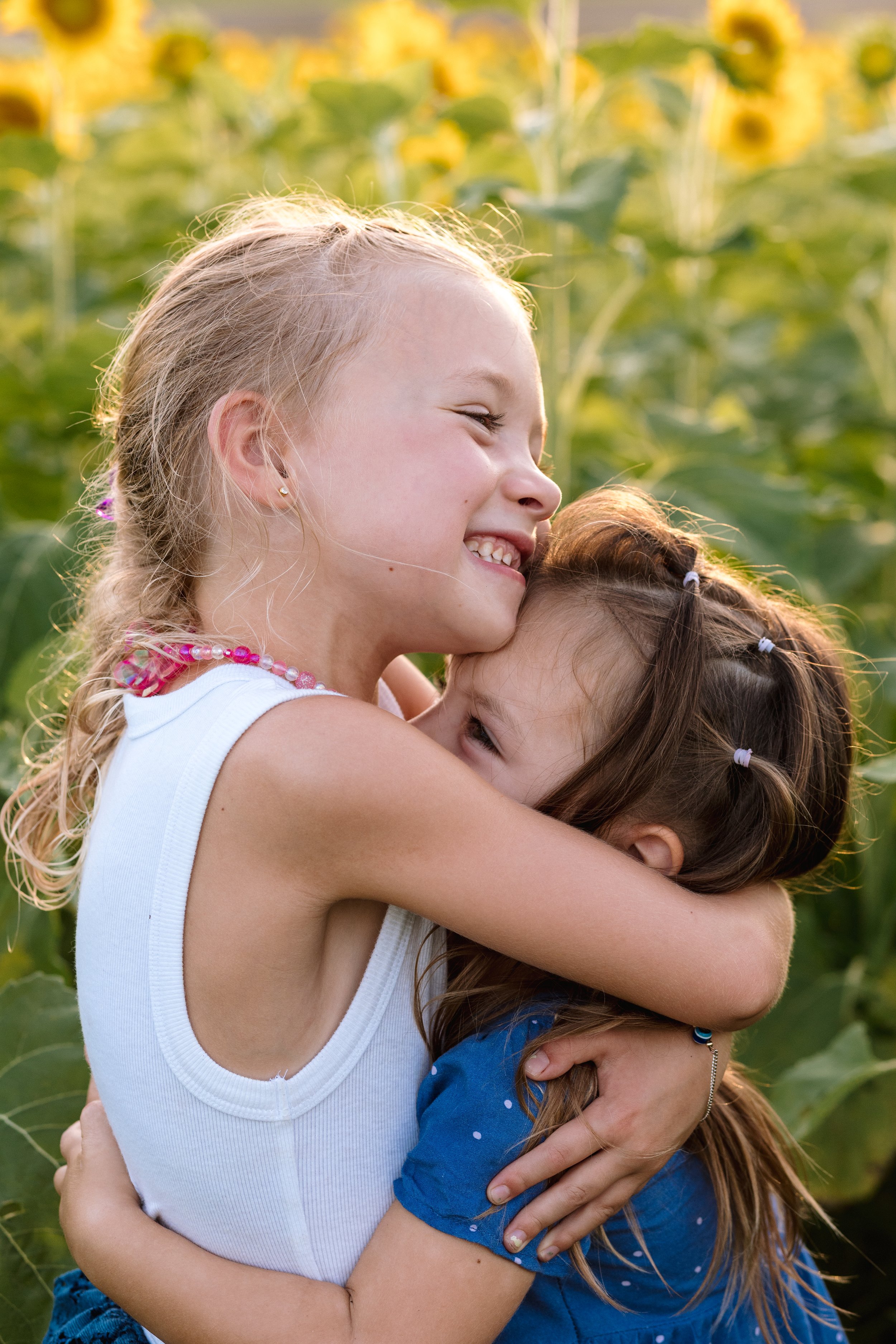 Sisters hugging in a field of sunflowers in Northern Virginia