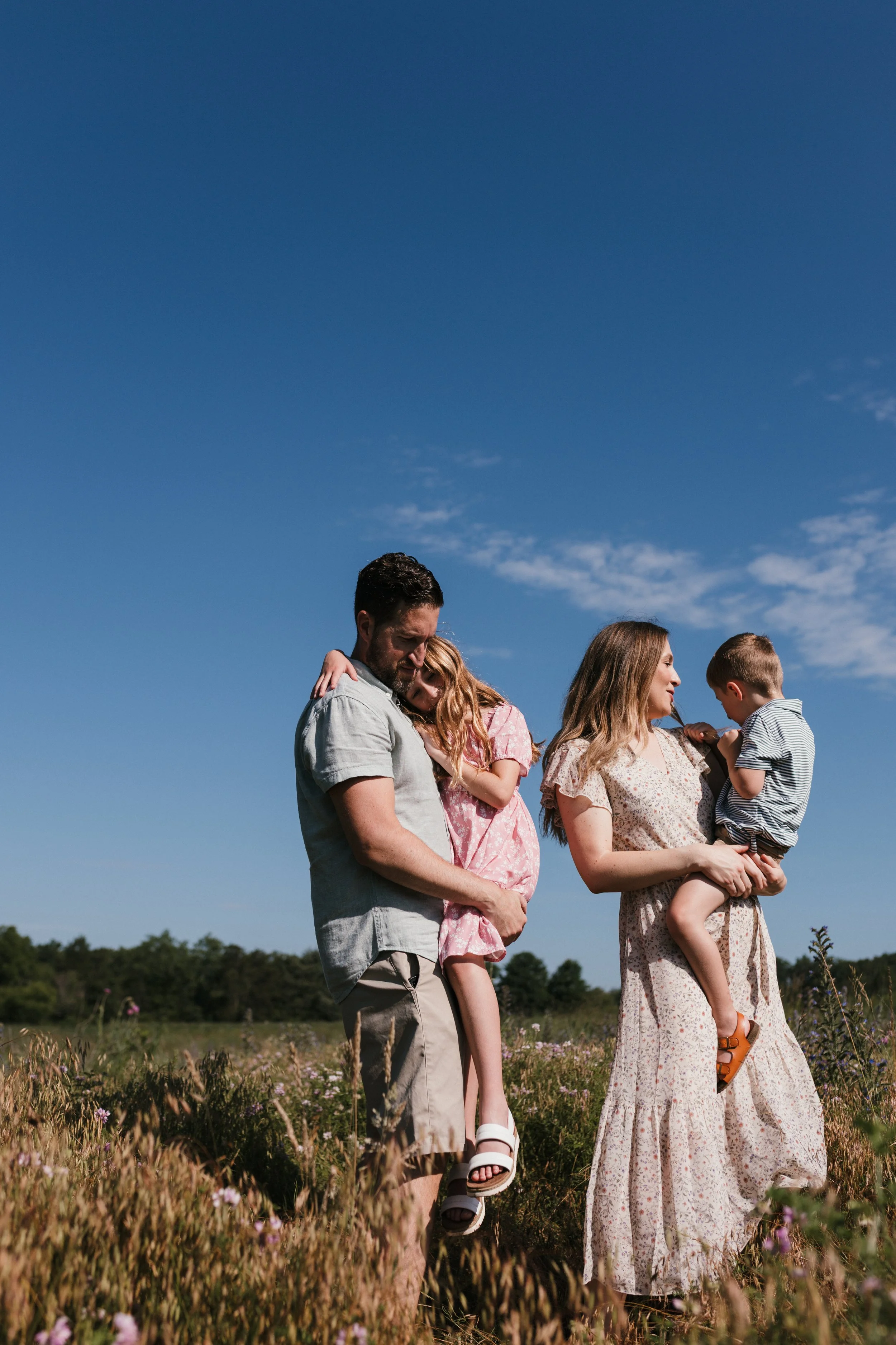 Family standing close together beneath an open sky at Manassas National Battlefield Park during a relaxed family photography session.