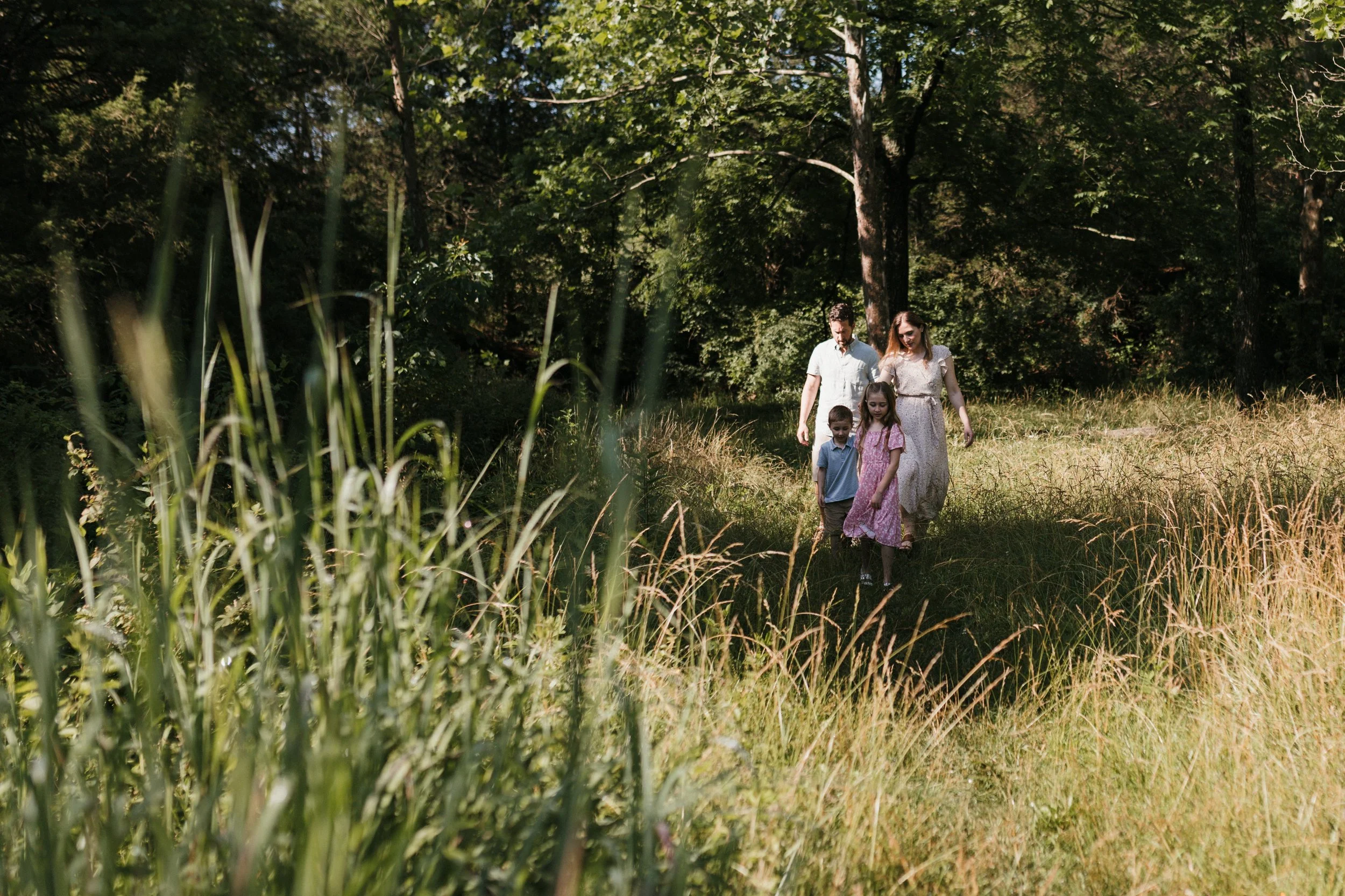 Family walking together through tall grass at Manassas National Battlefield Park during a relaxed family photography session.