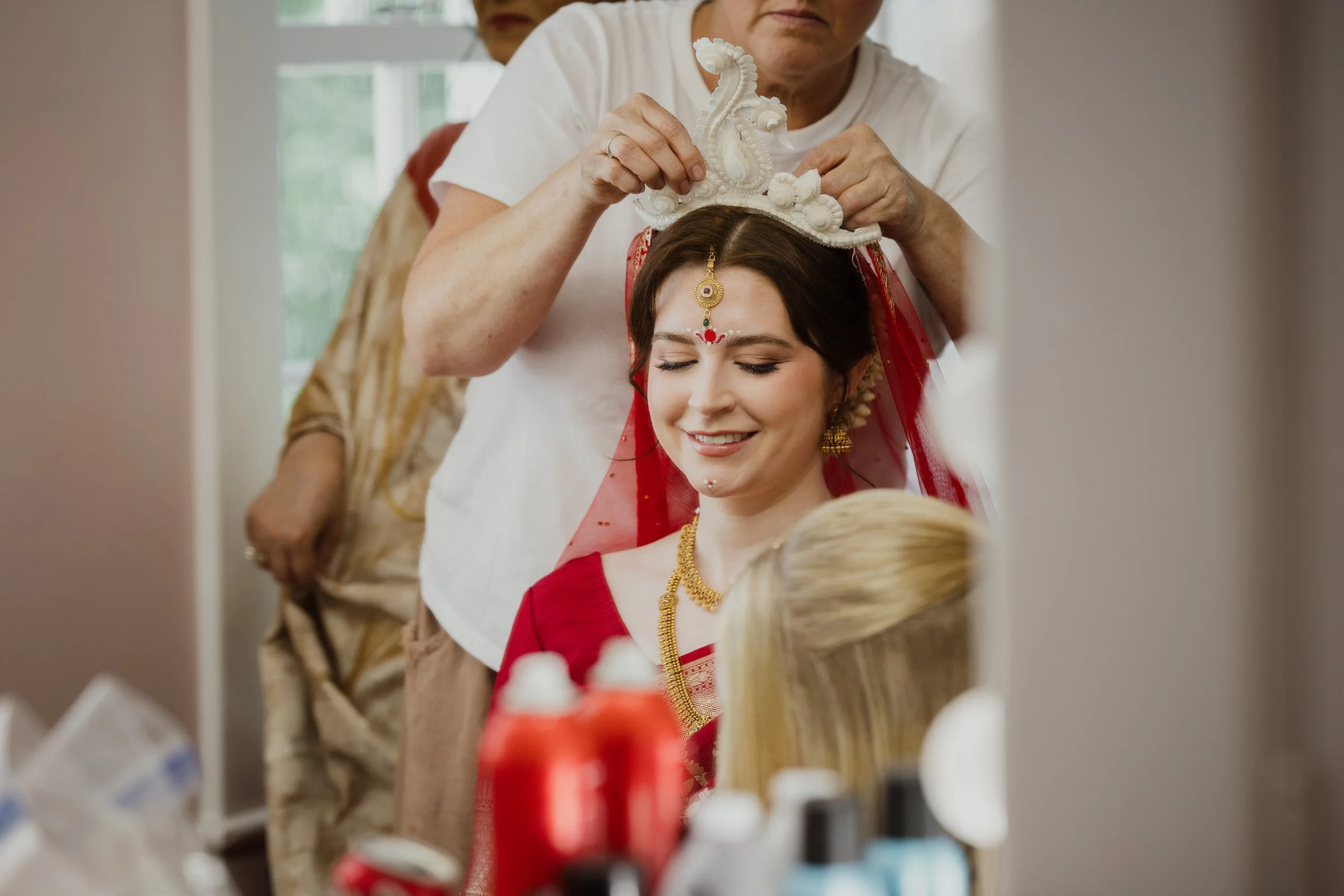 Bride smiling as a traditional bridal headpiece is placed during getting ready at Raspberry Plain Manor in Northern Virginia.