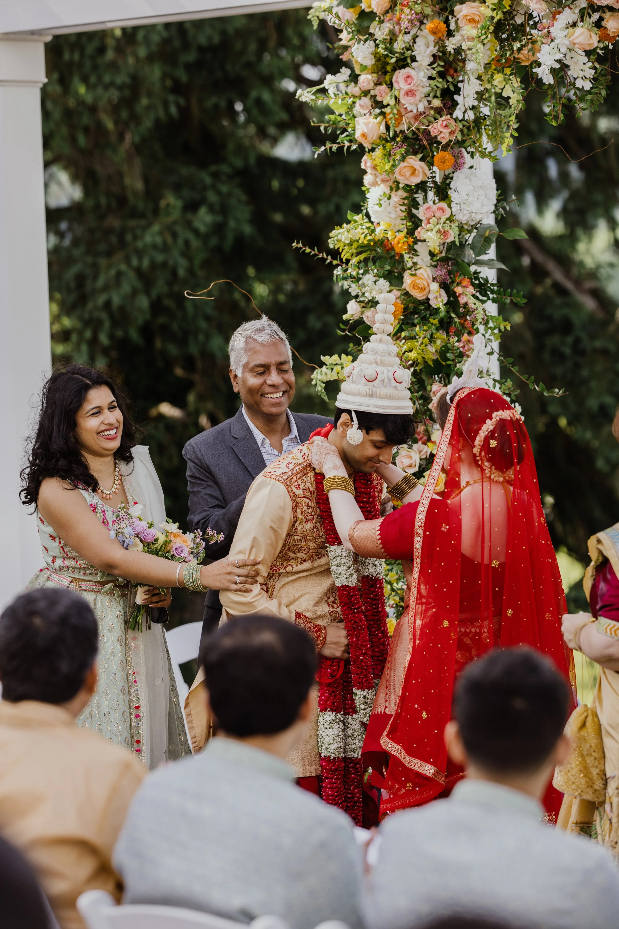 Bride placing a floral garland on the groom during a South Asian wedding ceremony at Raspberry Plain Manor.