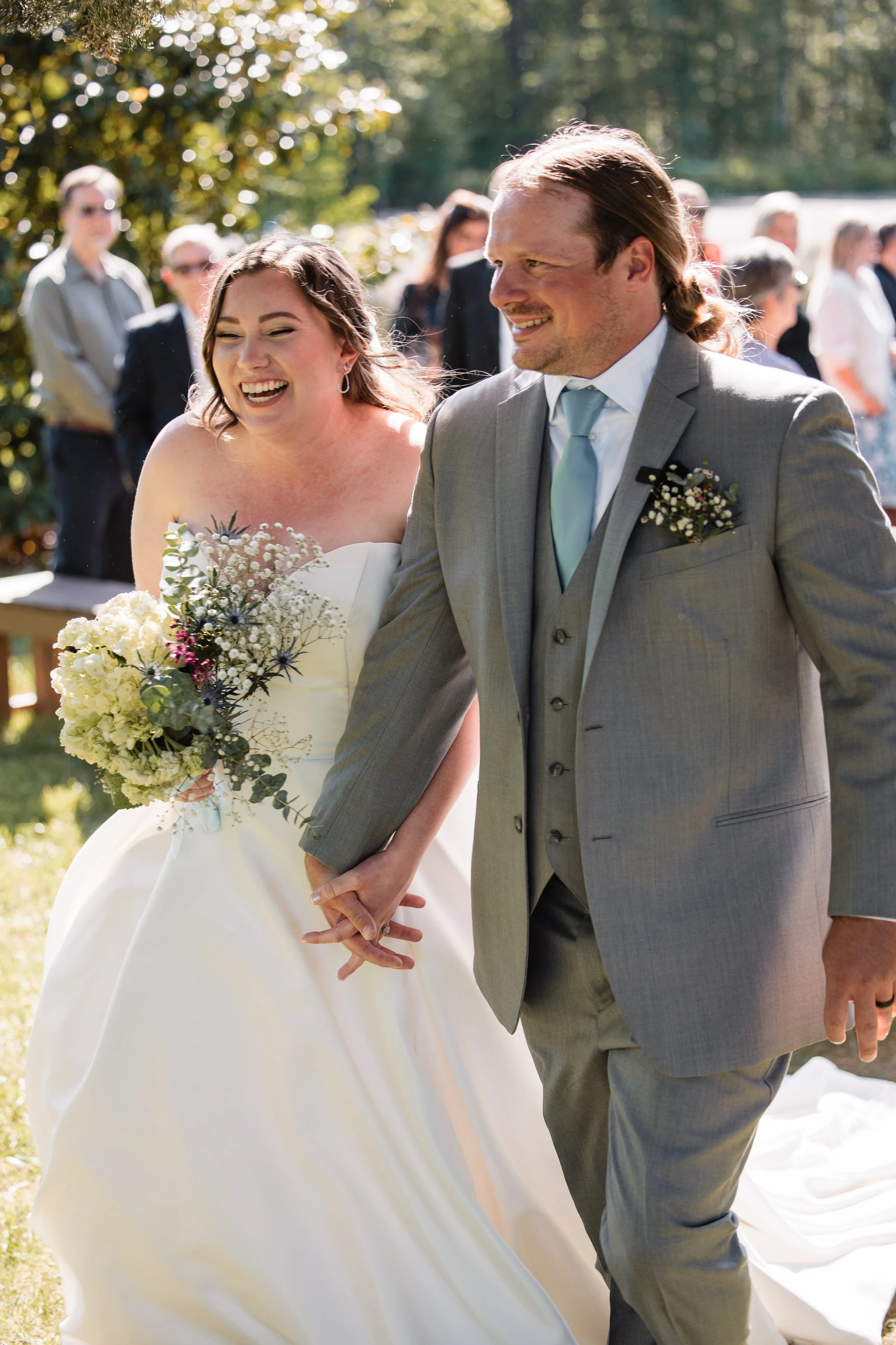 Bride and groom walking down the aisle smiling after their waterfront ceremony at Persimmon Creek Barn in Hanover County Virginia.