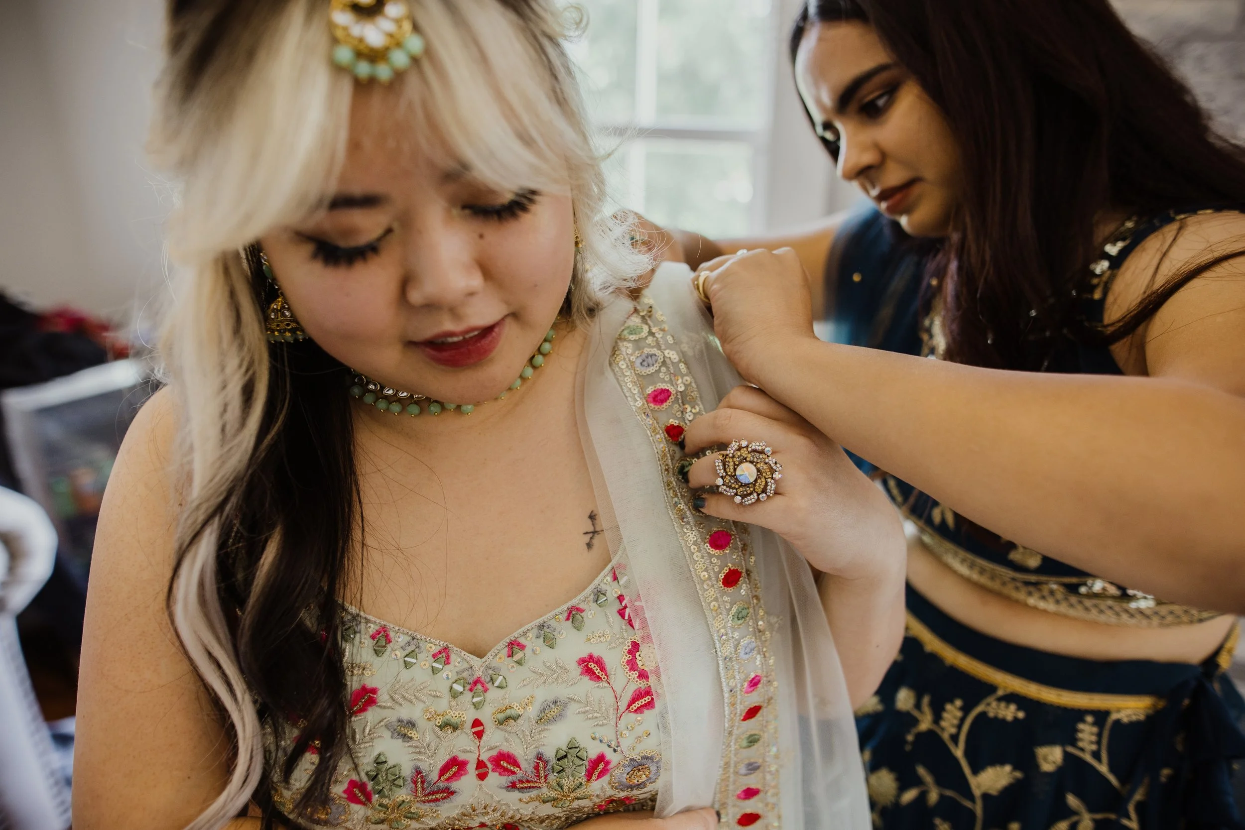Bridesmaids helping each other get ready before a multicultural wedding ceremony at Raspberry Plain Manor in Northern Virginia.