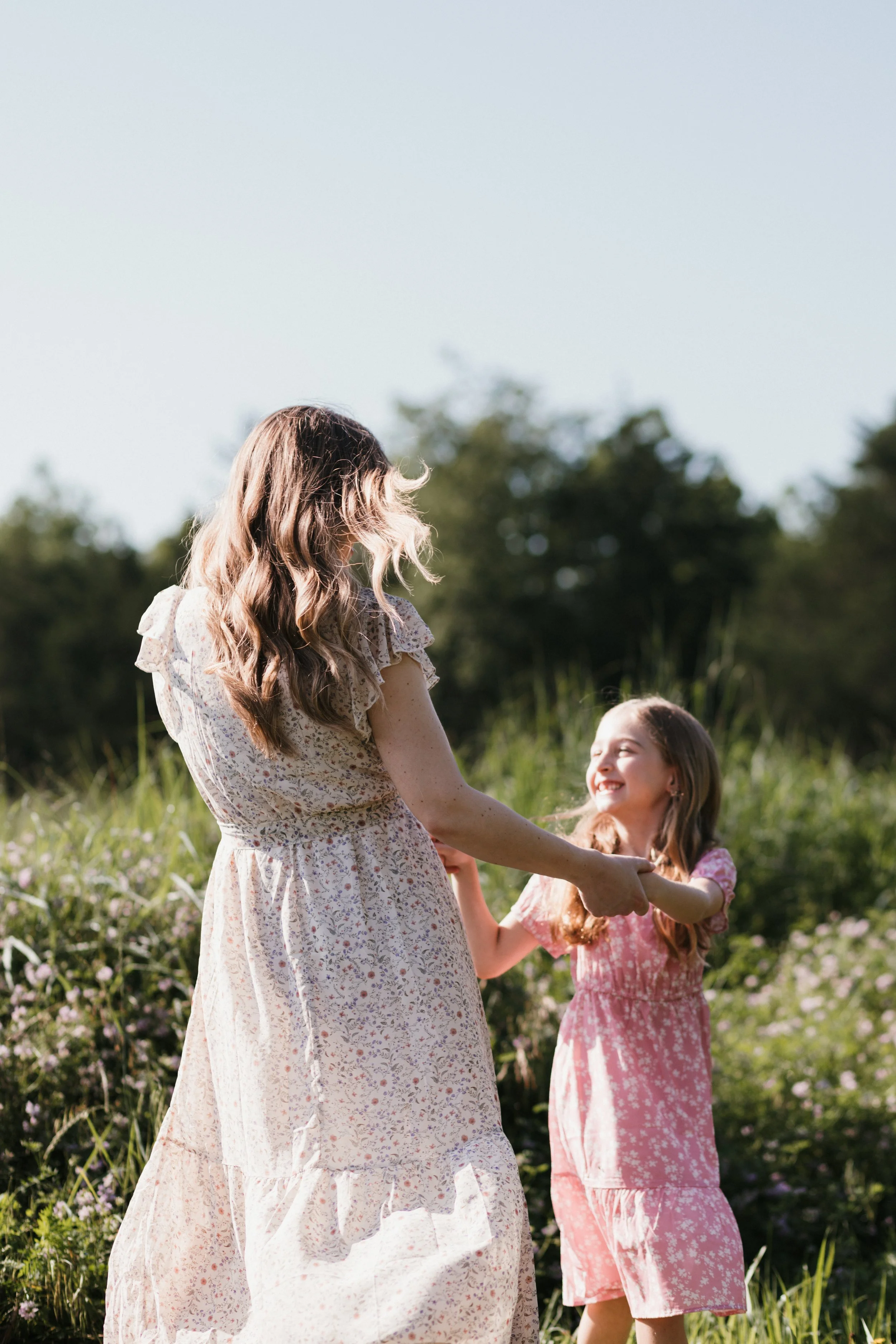 Mother and daughter holding hands and smiling together in an open field at Manassas National Battlefield Park during a relaxed family photography session.