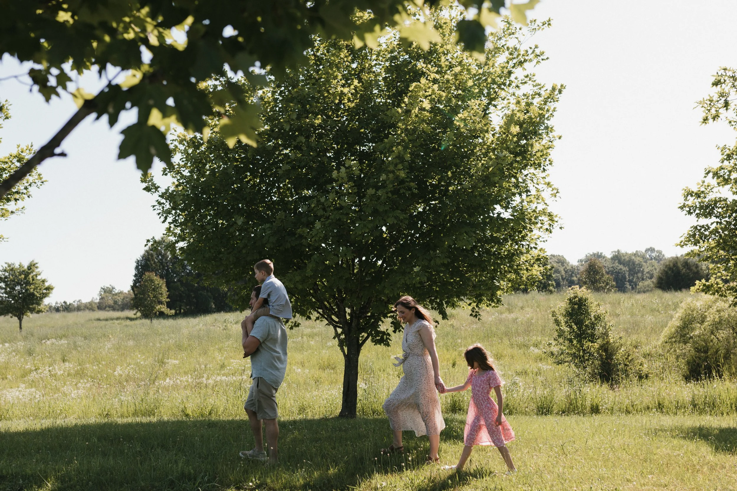 Family walking together through open fields at Manassas National Battlefield Park during a warm morning family photography session.