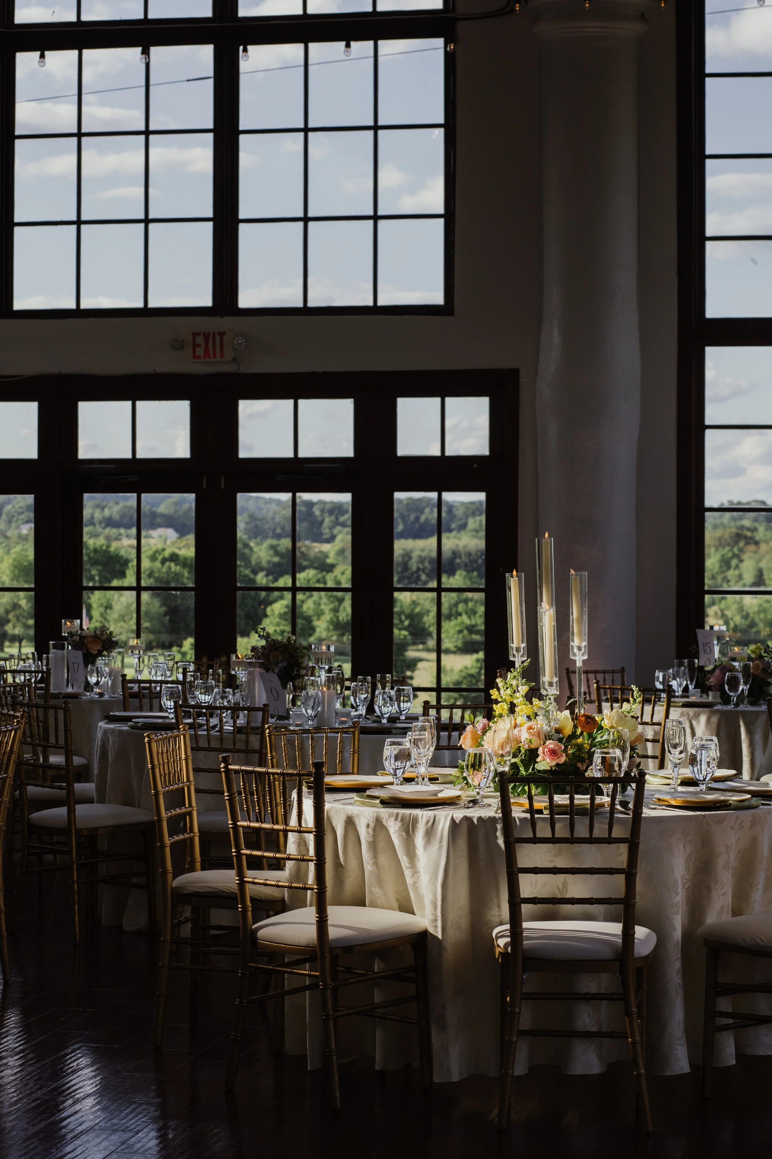 Reception space at Raspberry Plain Manor in Leesburg, Virginia with tall windows, candlelit centerpieces, and elegant wedding tables.