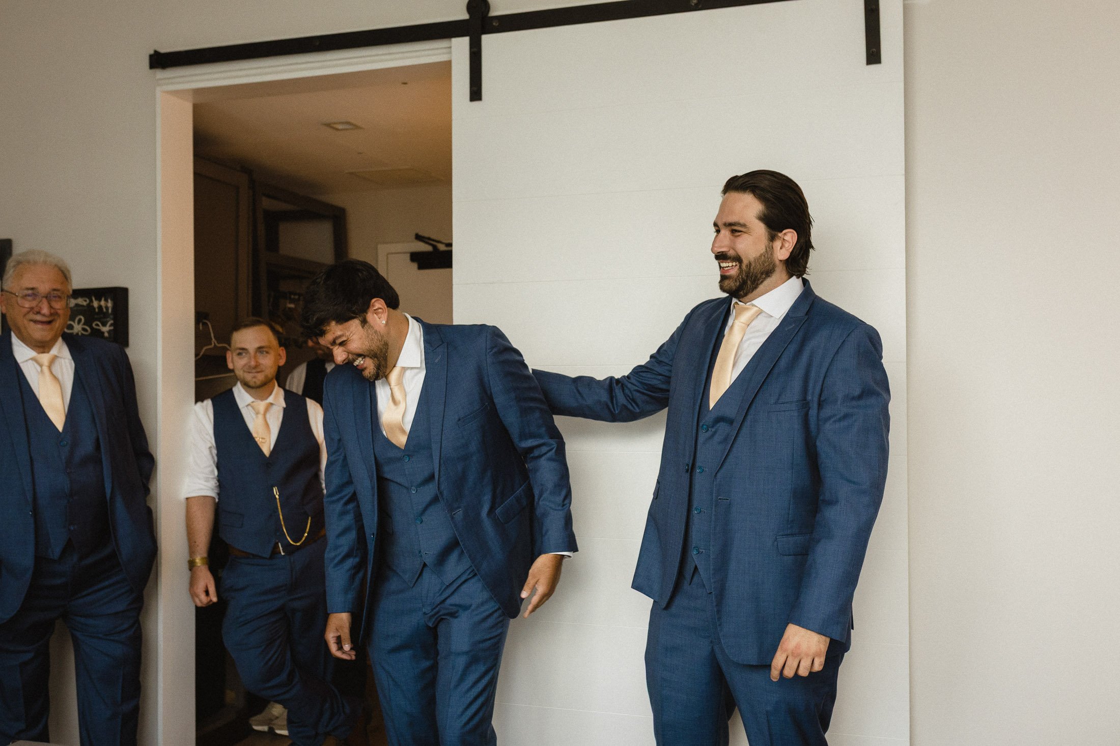 Groom laughing with groomsmen during candid wedding morning preparations in Washington DC