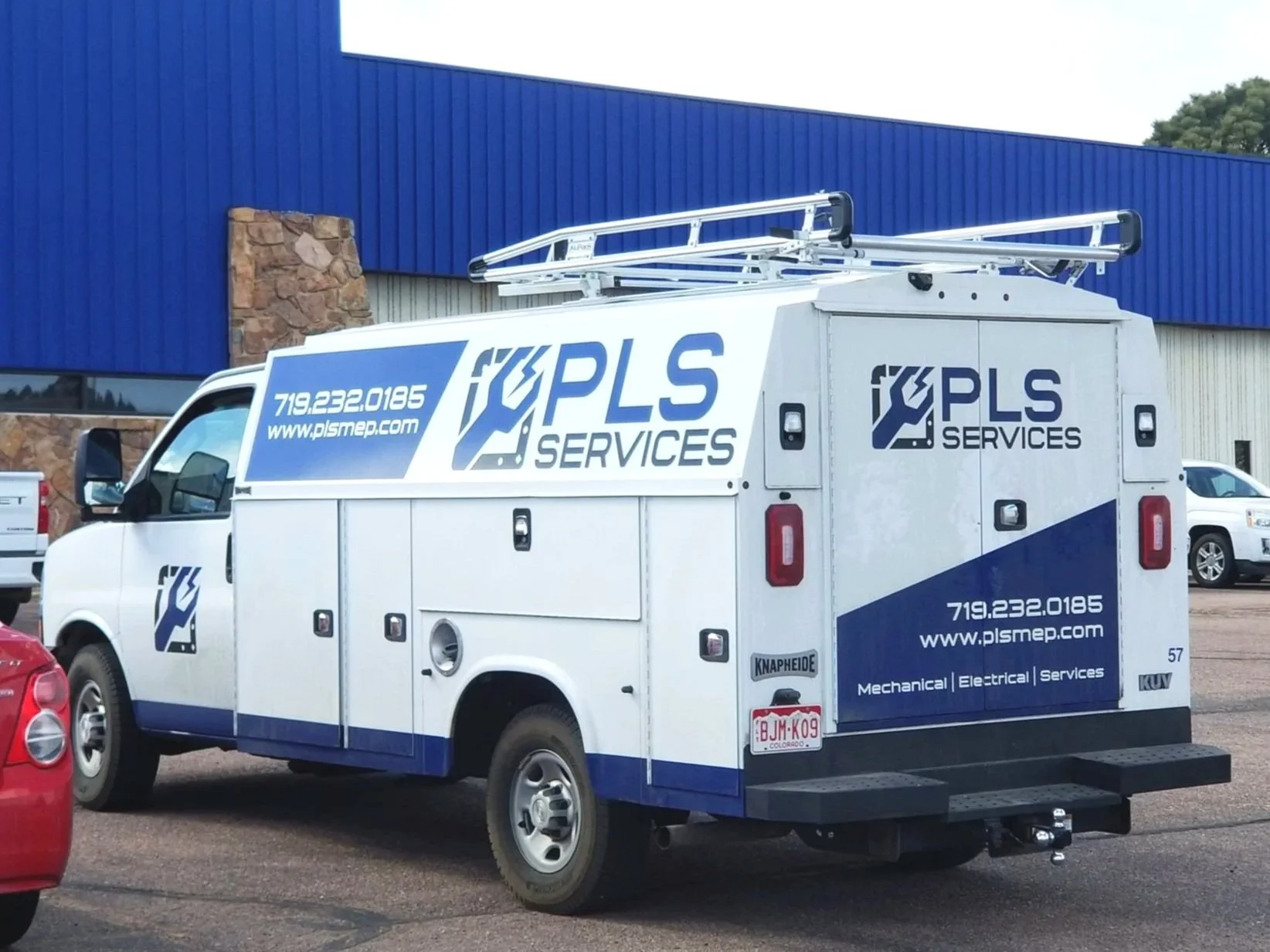 White utility truck with "PLS Services" logo parked in a lot, featuring a blue and white color scheme and text for contact information.