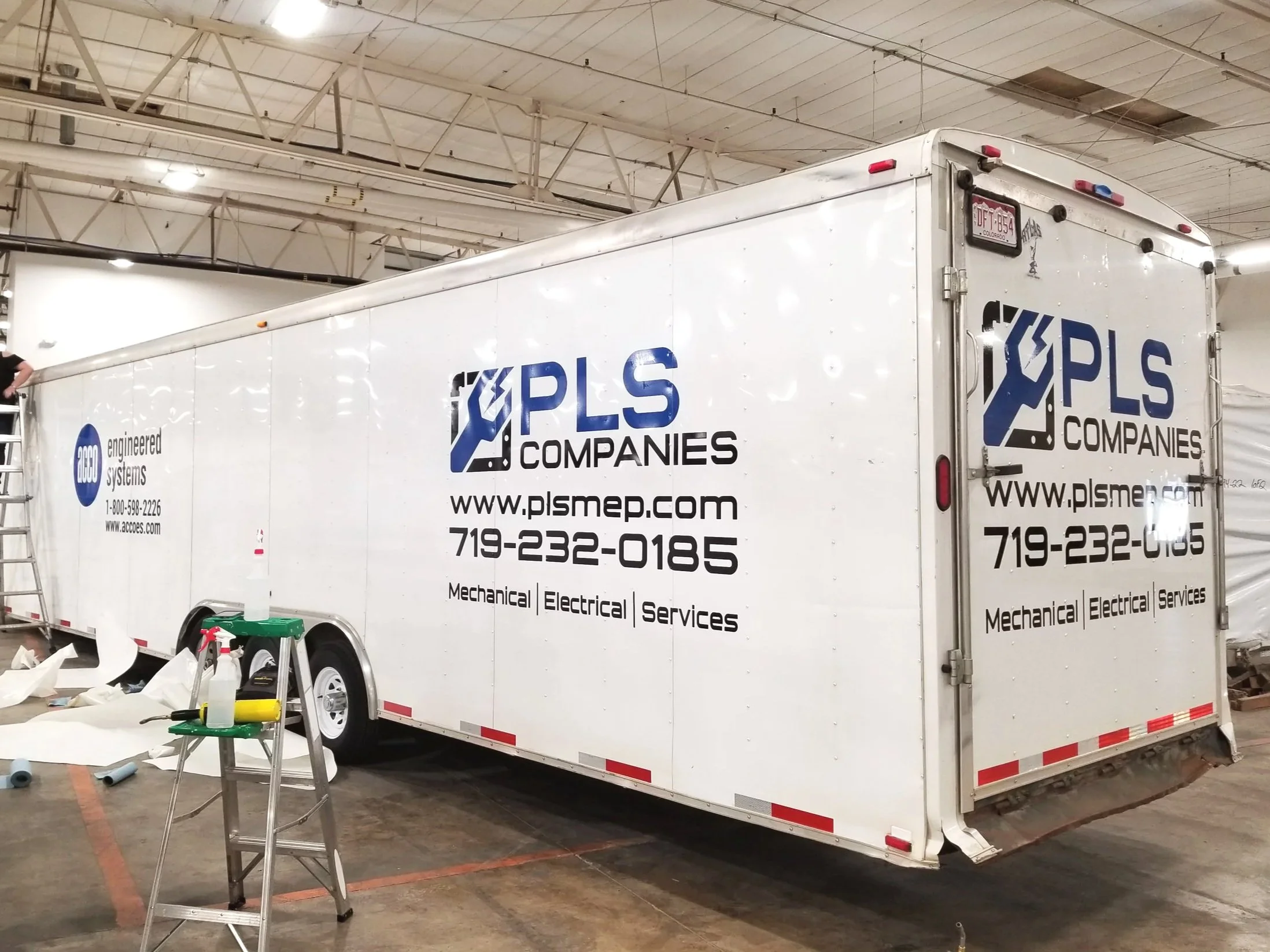 White trailer with PLS Companies logo and contact information inside a warehouse.