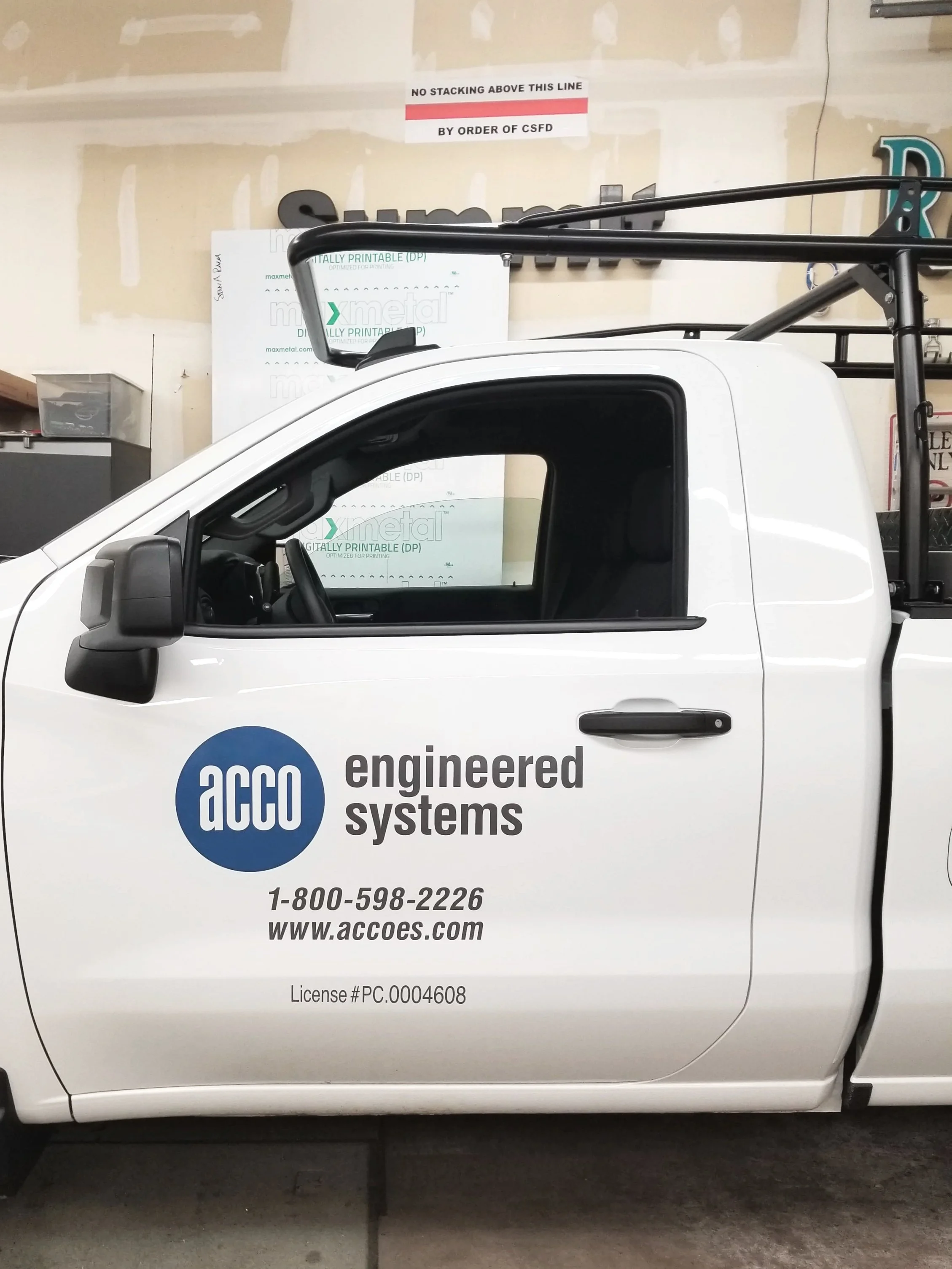 White truck with "ACCO Engineered Systems" logo, contact number, and website printed on the door, parked indoors.